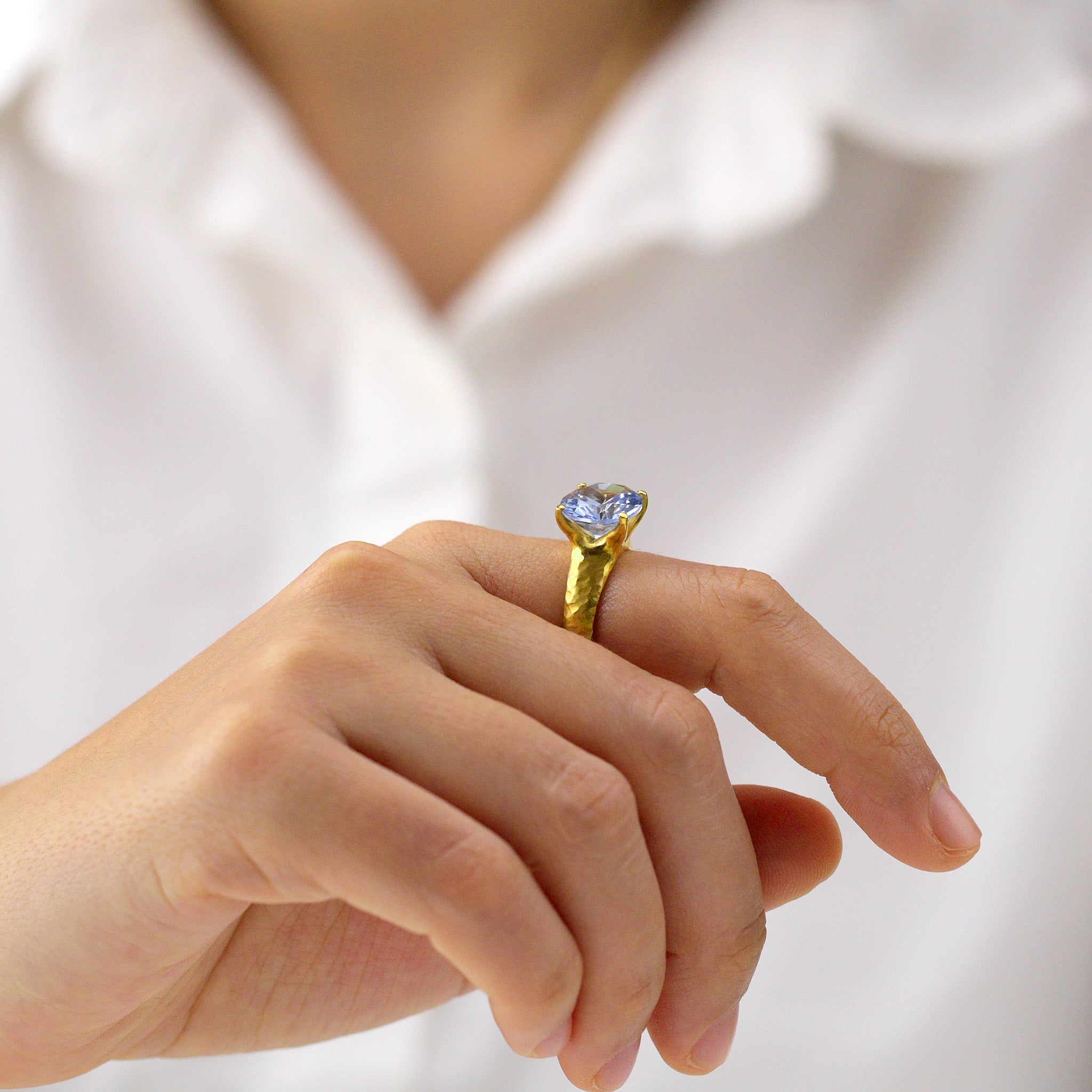 Model wearing an 18k Gold ring featuring four stems holding an elliptic Blue Topaz, combining rich color depth with a dignified presence.