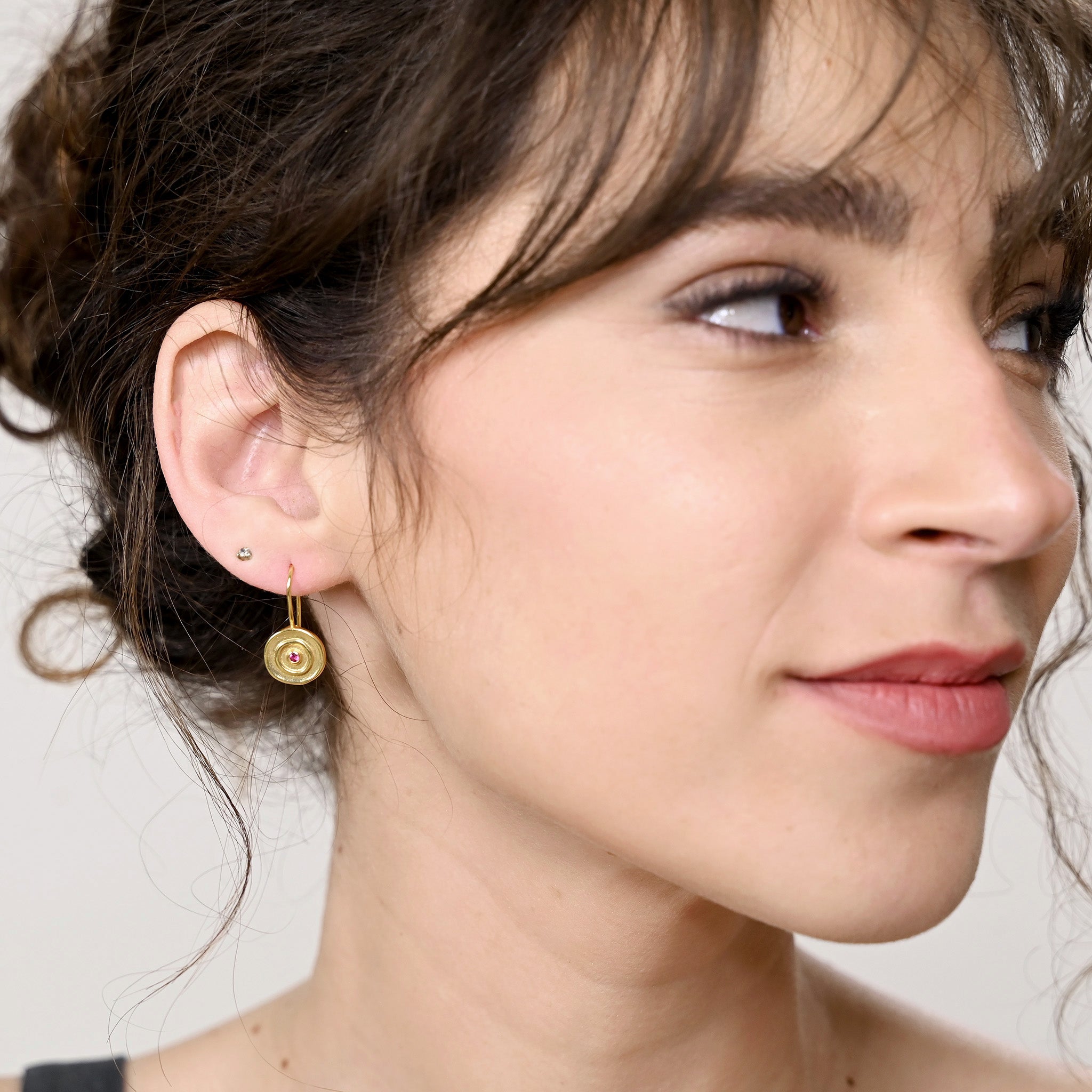 Model displaying an Hand-made 18k gold round drop earrings with a central Ruby gemstone, inspired by ancient Egyptian Pharaohs' gold jewelry.
