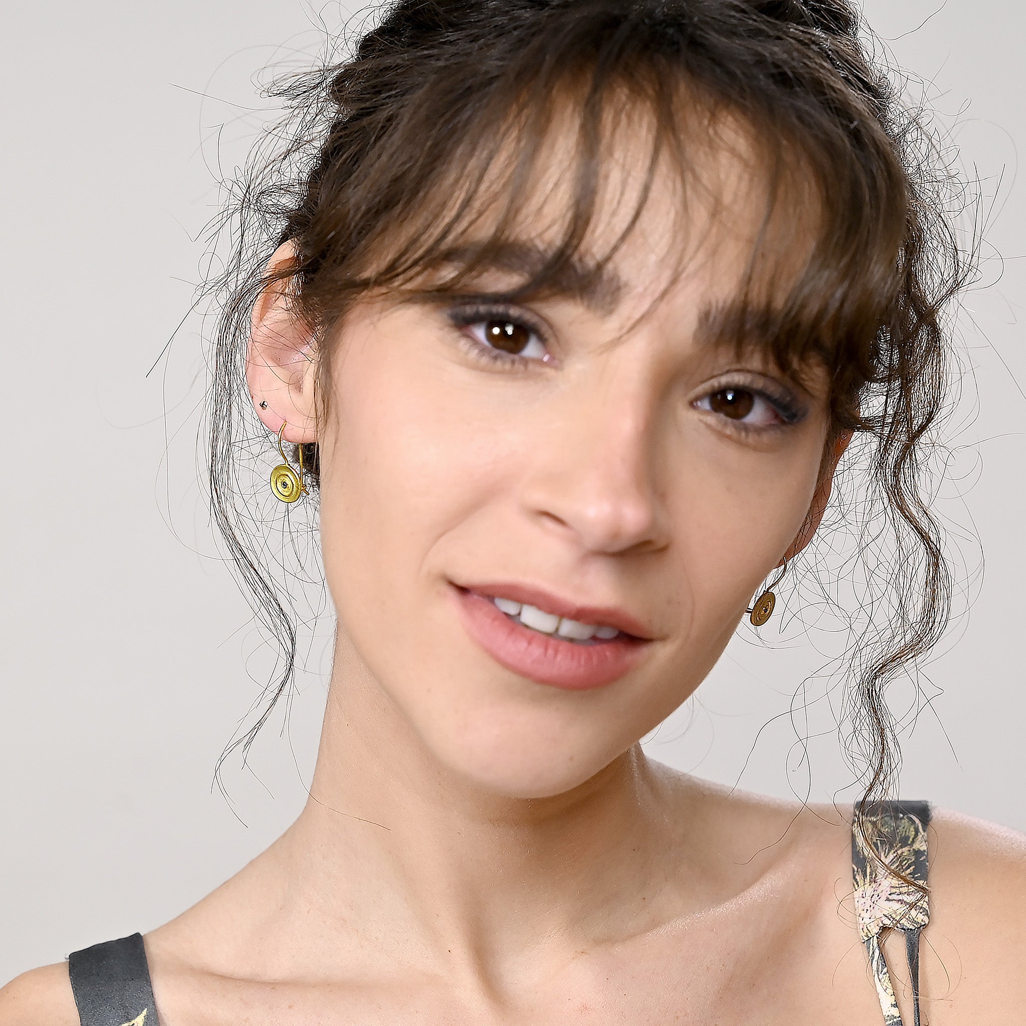 Model displaying an Hand-made 18k gold round drop earrings with a central Sapphire gemstone, inspired by ancient Egyptian Pharaohs' gold jewelry.