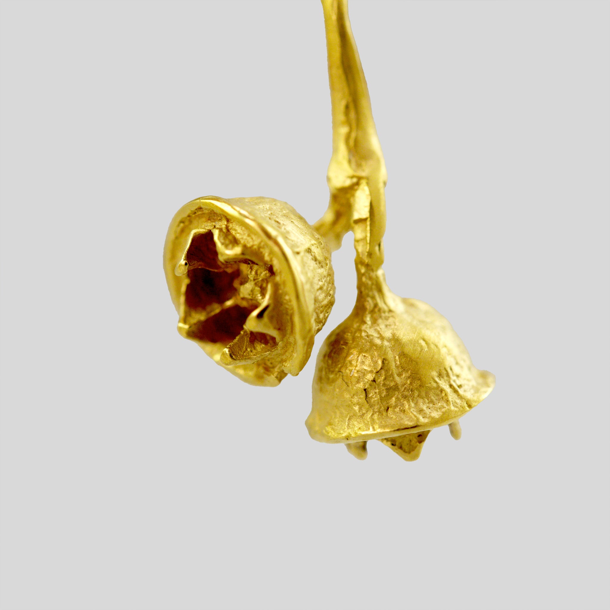 close up of an 18k Gold necklace modeled after a eucalyptus branch, featuring two detailed dried seed pods, offering a realistic and natural look, ideal for everyday wear.