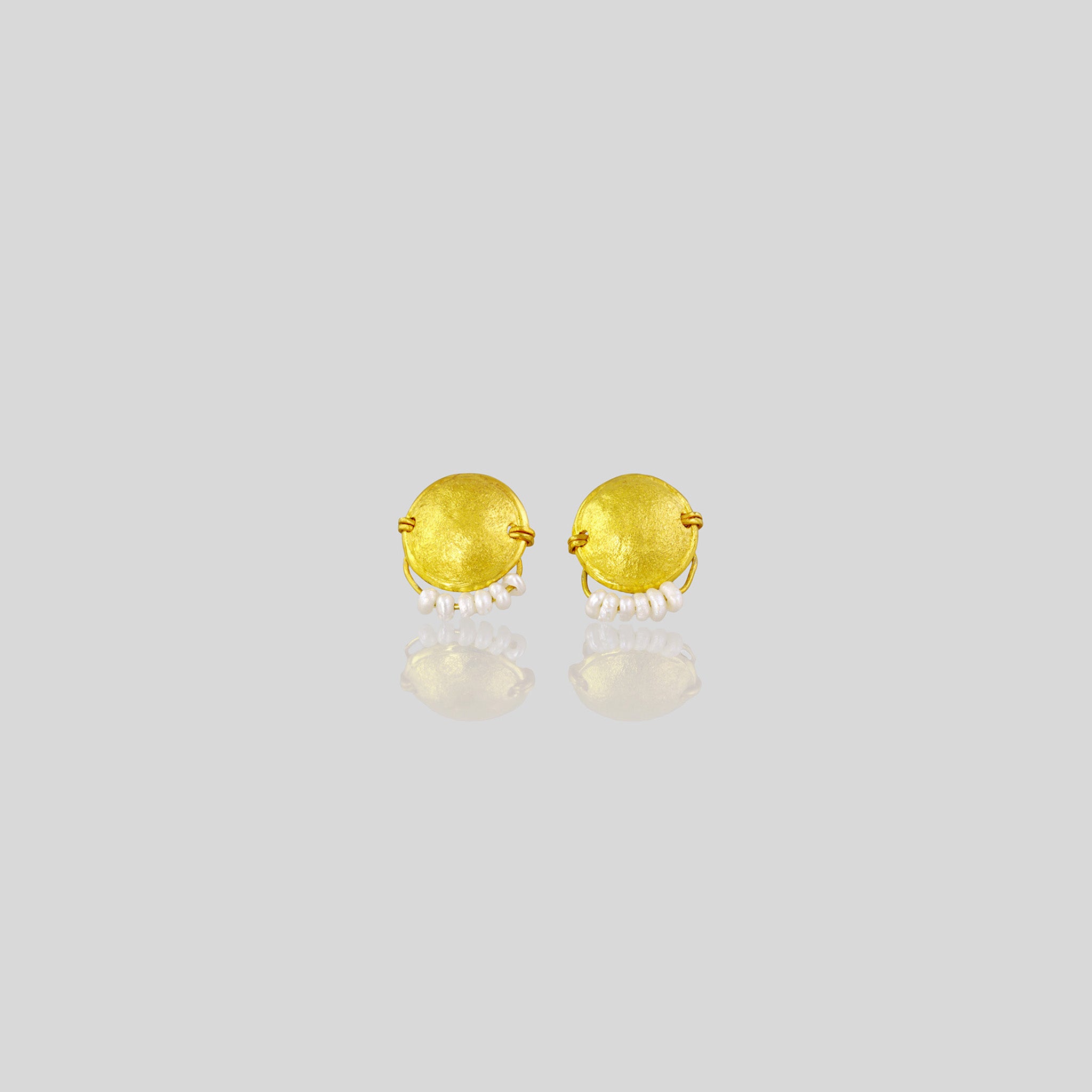 Hand-crafted 18k gold stud earrings with a curved disk design, adorned with a delicate golden thread and tiny pearls hanging from a golden bow.