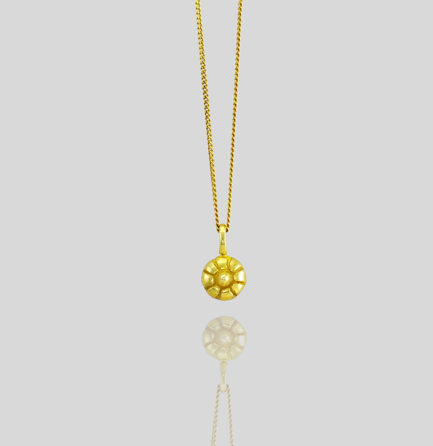 close up of a Pendant crafted to resemble the Mallow fruit, made from luxurious gold, capturing its delicate and luminous natural form.