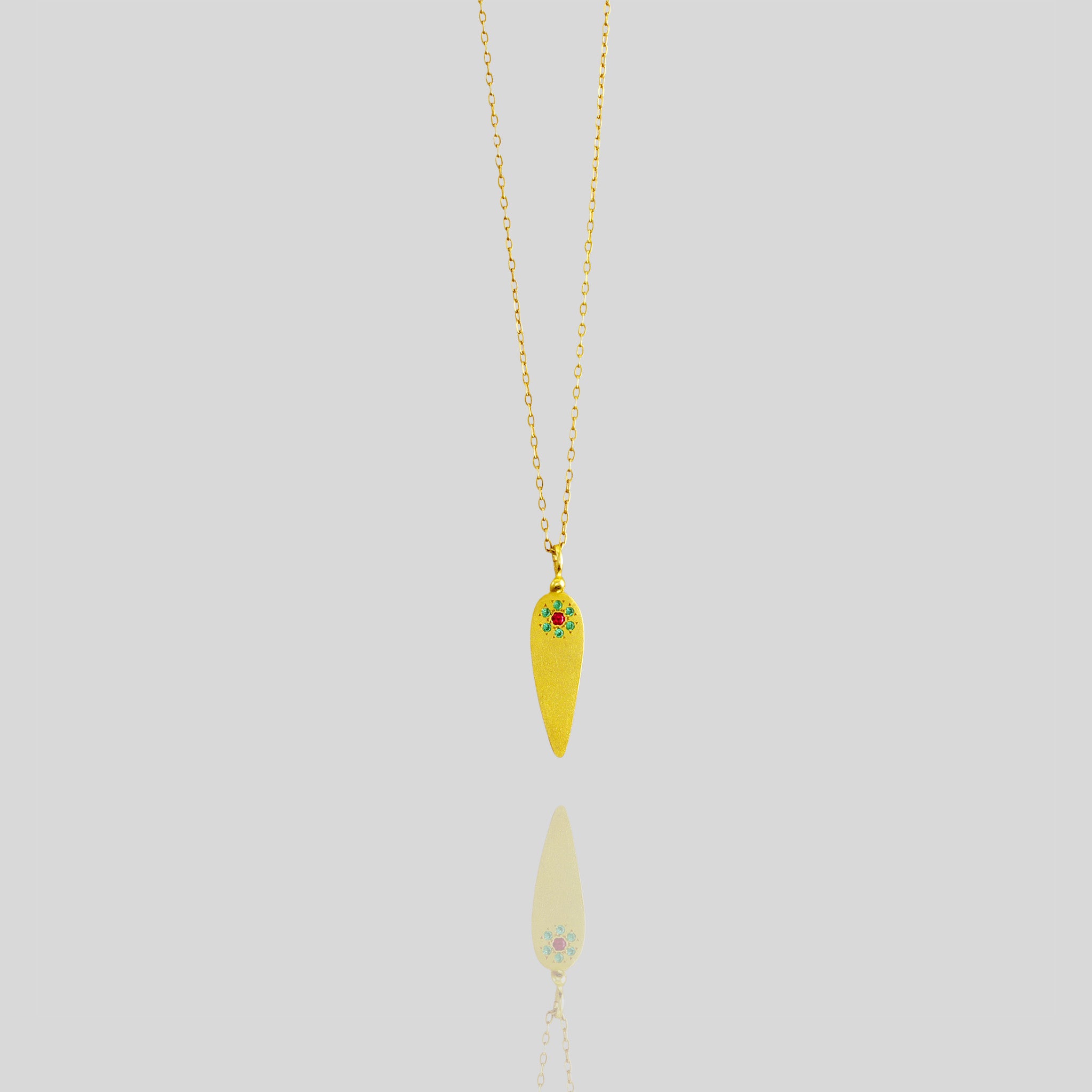 Yellow gold pendant crafted in the form of a delicate leaf, adorned with ruby and emerald gemstones arranged to resemble a small, intricate flower.