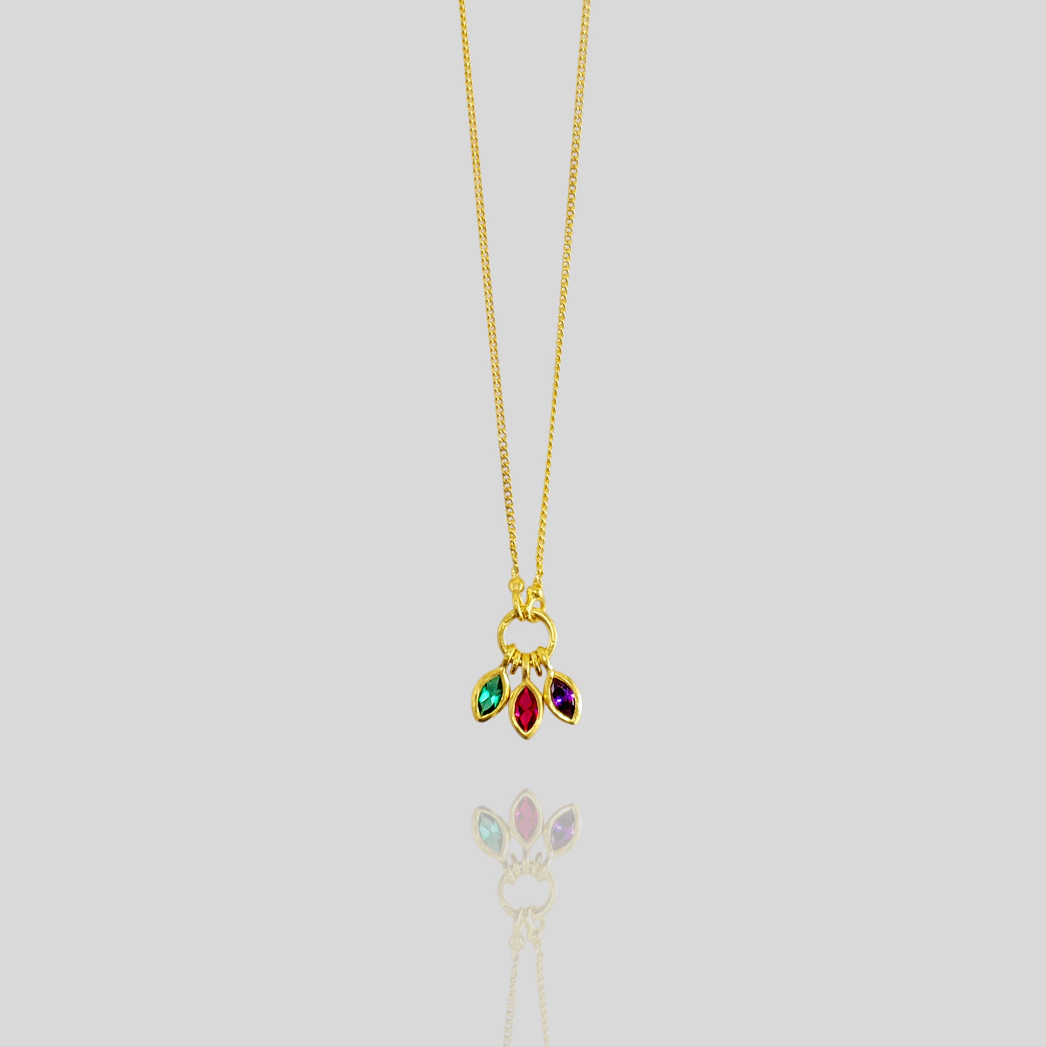 Gold marquee pendant with three expertly cut gemstones - ruby, emerald, and sapphire - elegantly intertwined, showcasing a blend of colors and radiance.