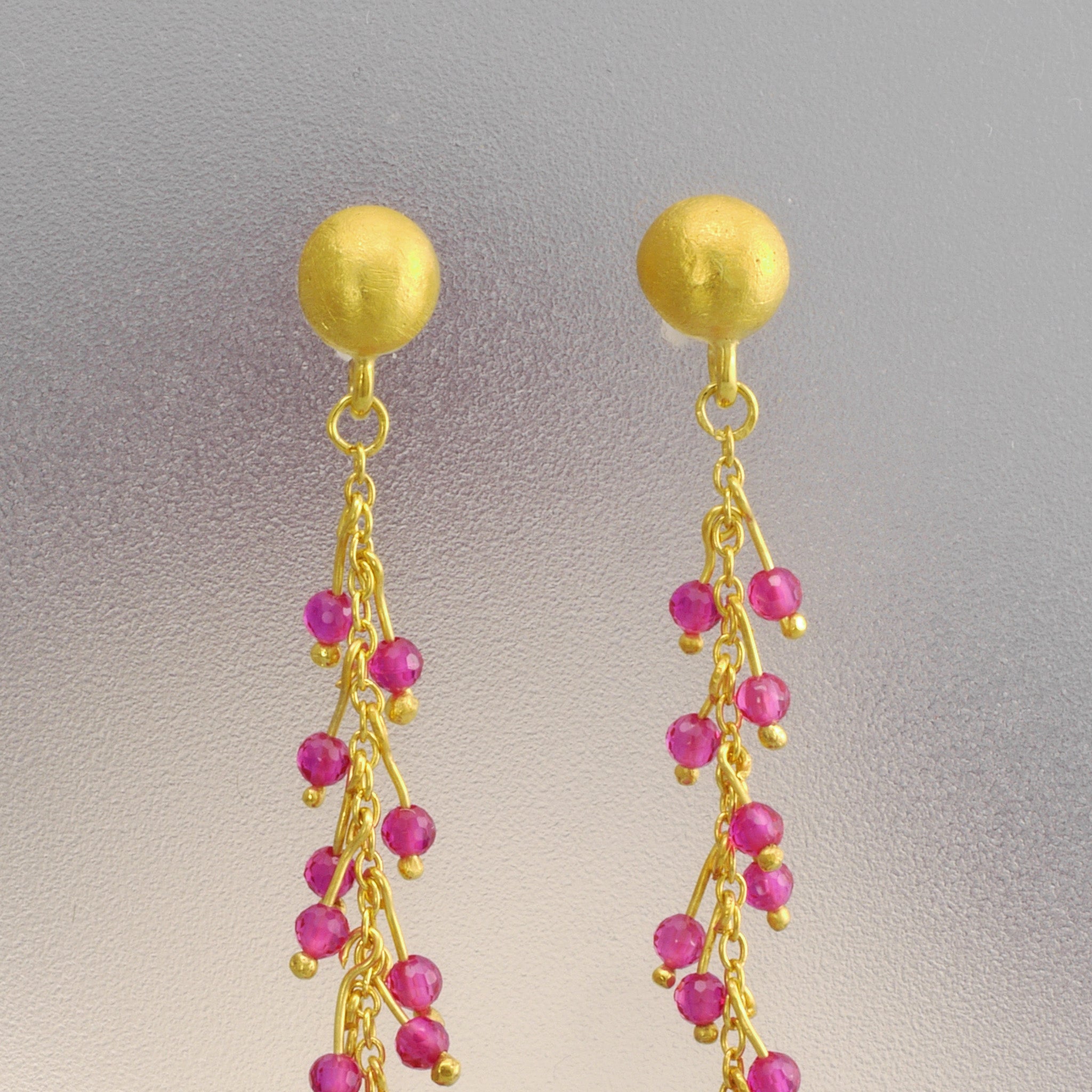 Detail photo of 18k gold studs adorned with radiant ruby beads on shimmering gold threads, inspired by Venus emerging from the sea.