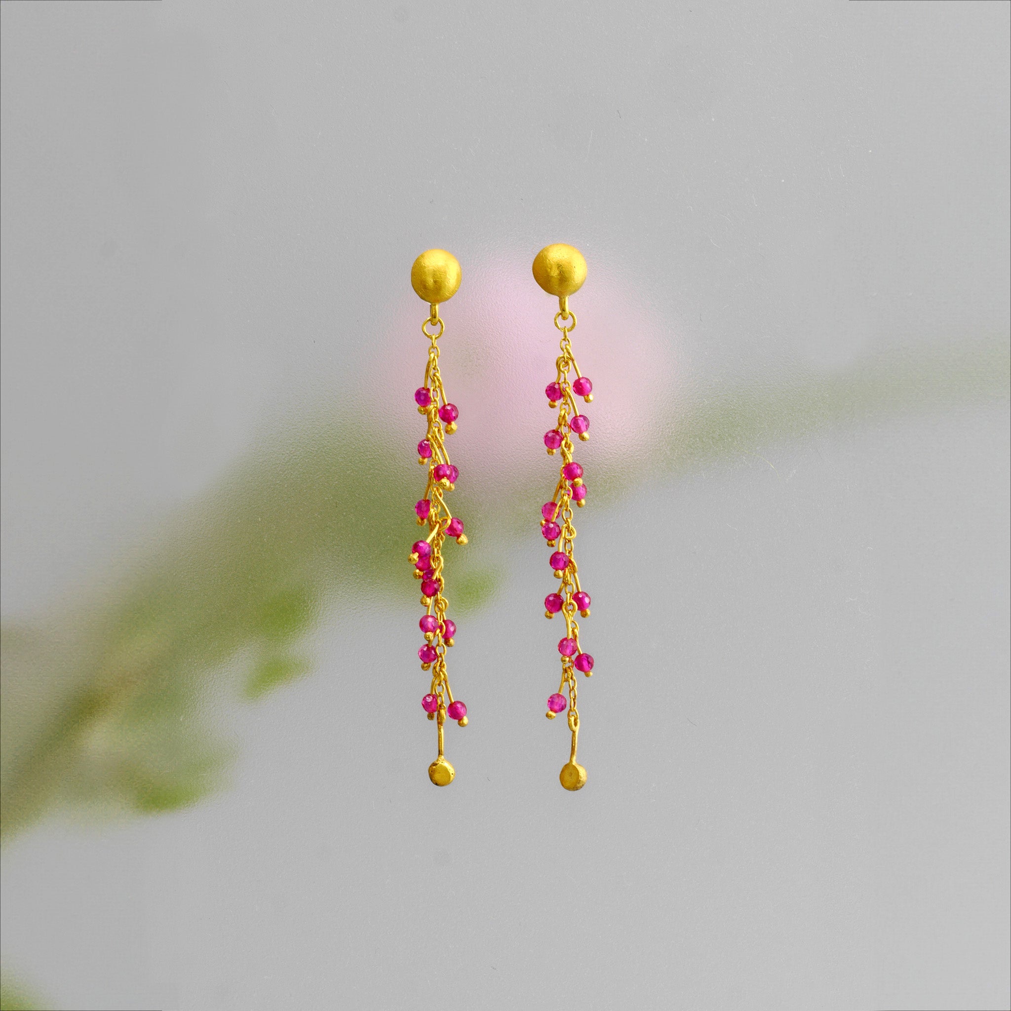 18k gold studs adorned with radiant ruby beads on shimmering gold threads, inspired by Venus emerging from the sea.