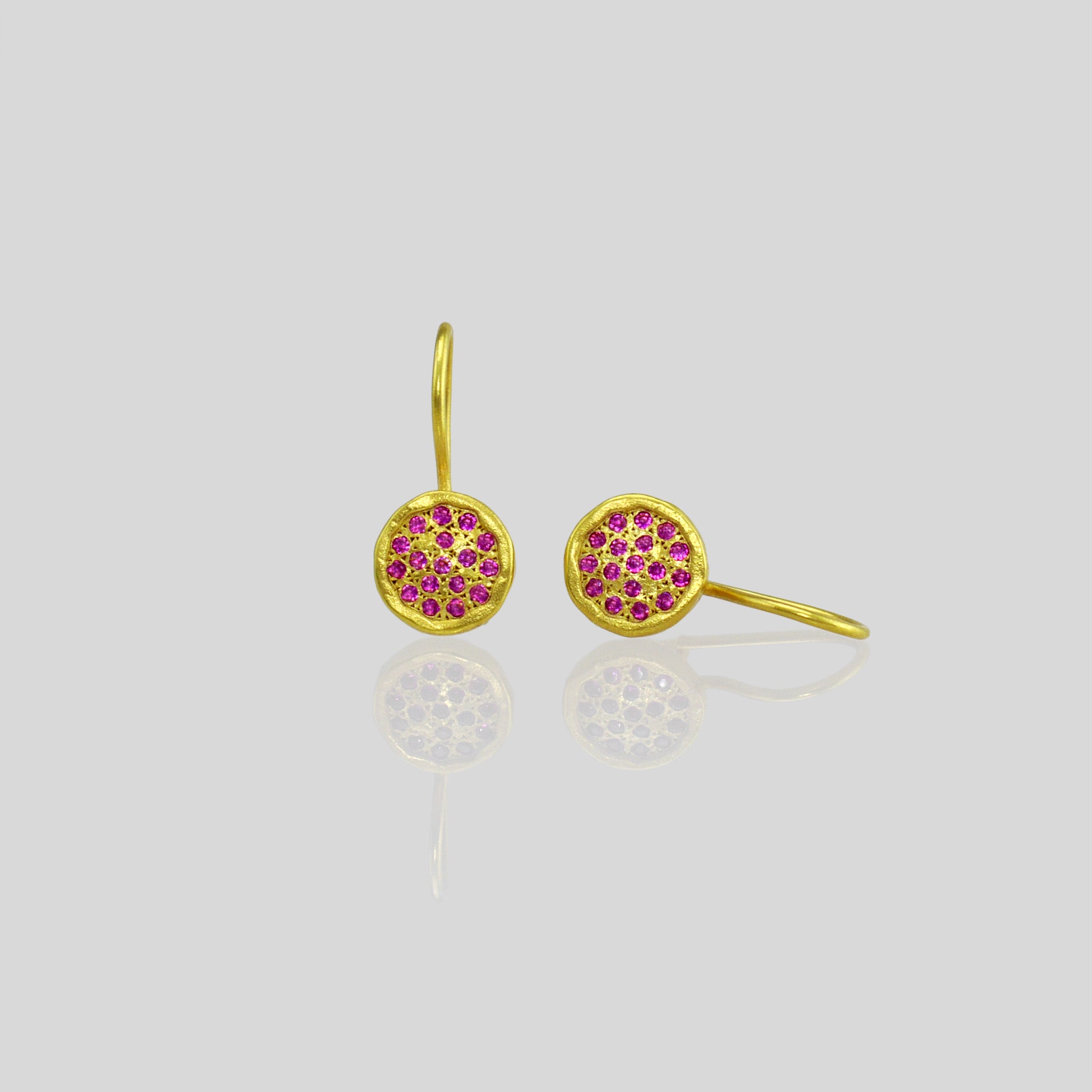 Close up of 18k Gold drop earrings adorned with twinkling ruby gemstones, reminiscent of a starry night sky.