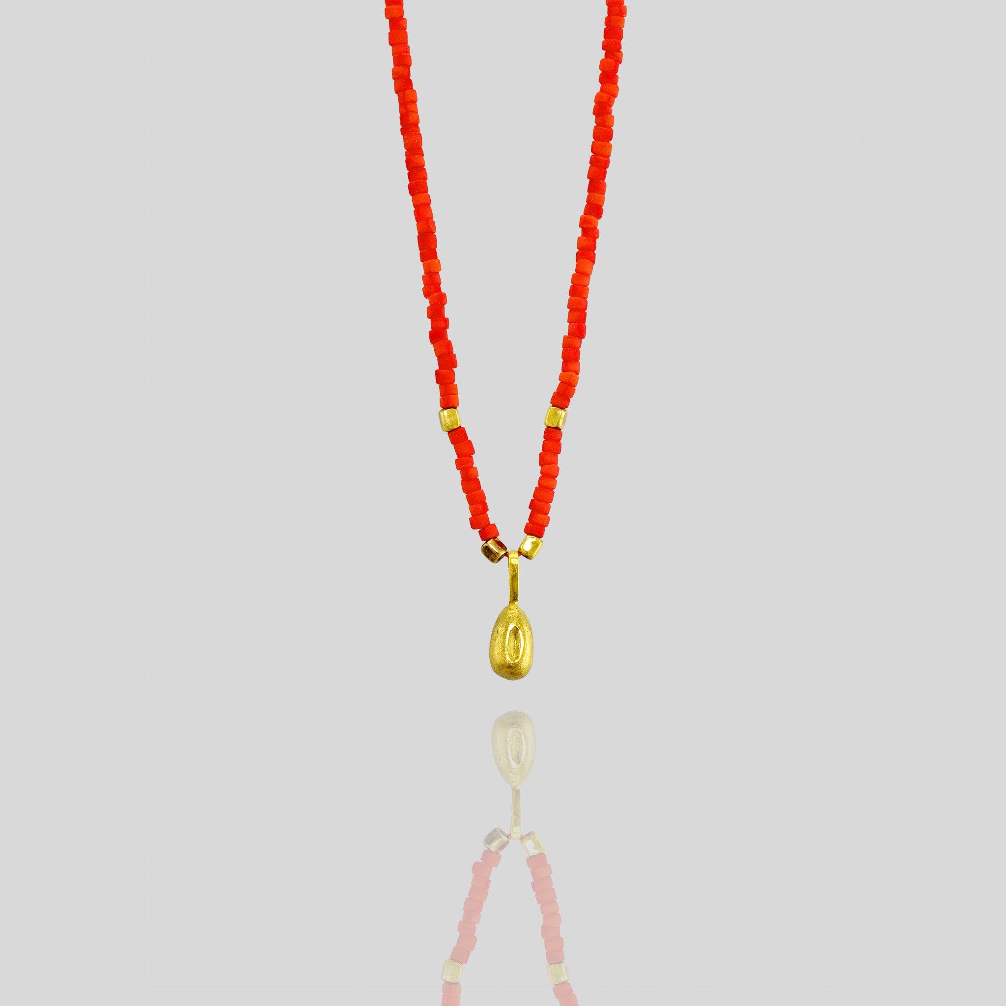 Playful and elegant Koral necklace with a natural gold seed charm, adding a colorful and mischievous touch to any outfit.