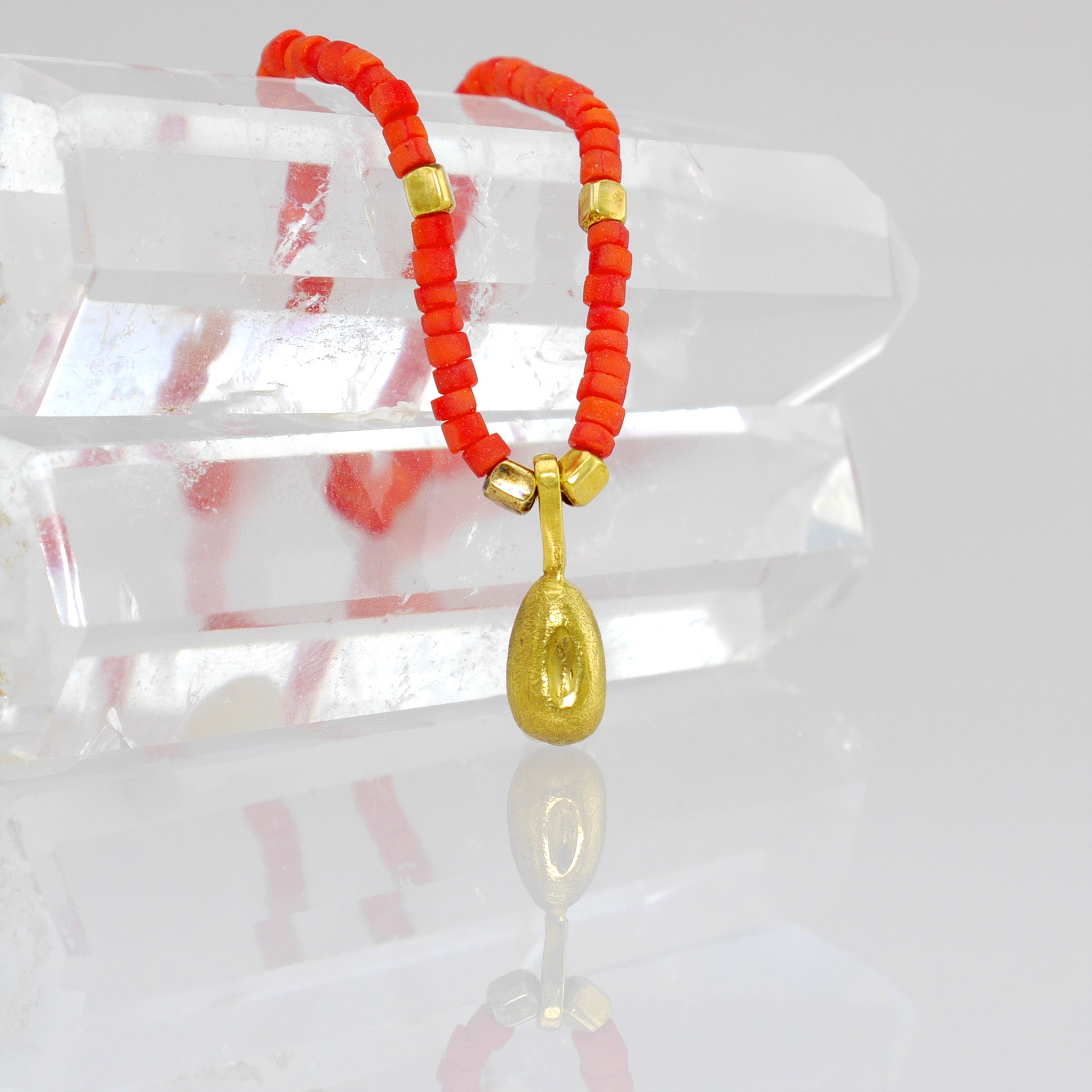 Close up of a Playful and elegant Koral necklace with a natural gold seed charm, adding a colorful and mischievous touch to any outfit.