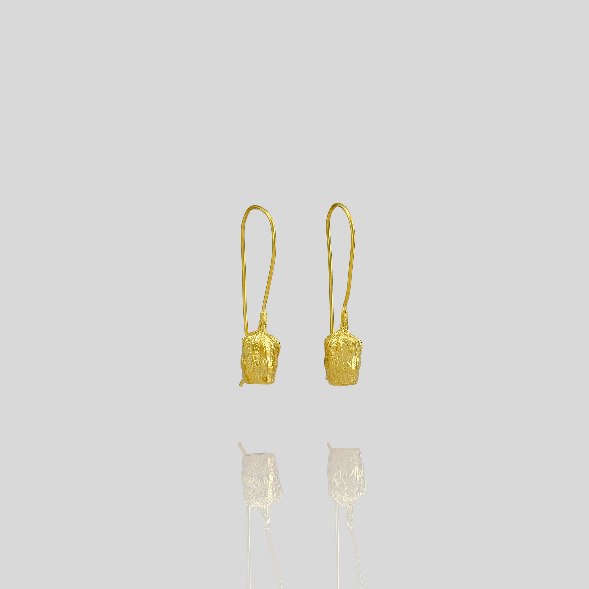 Gold drop earrings featuring a bell-shaped seed, which is a replica of a dried seed collected from nature.