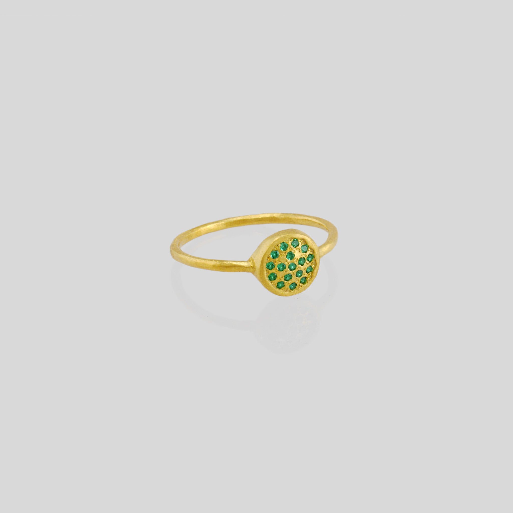 Delicate hand-made gold ring with a circular plate set with tiny Emerald gemstones. The sparkle from the stones resembles a starry night.