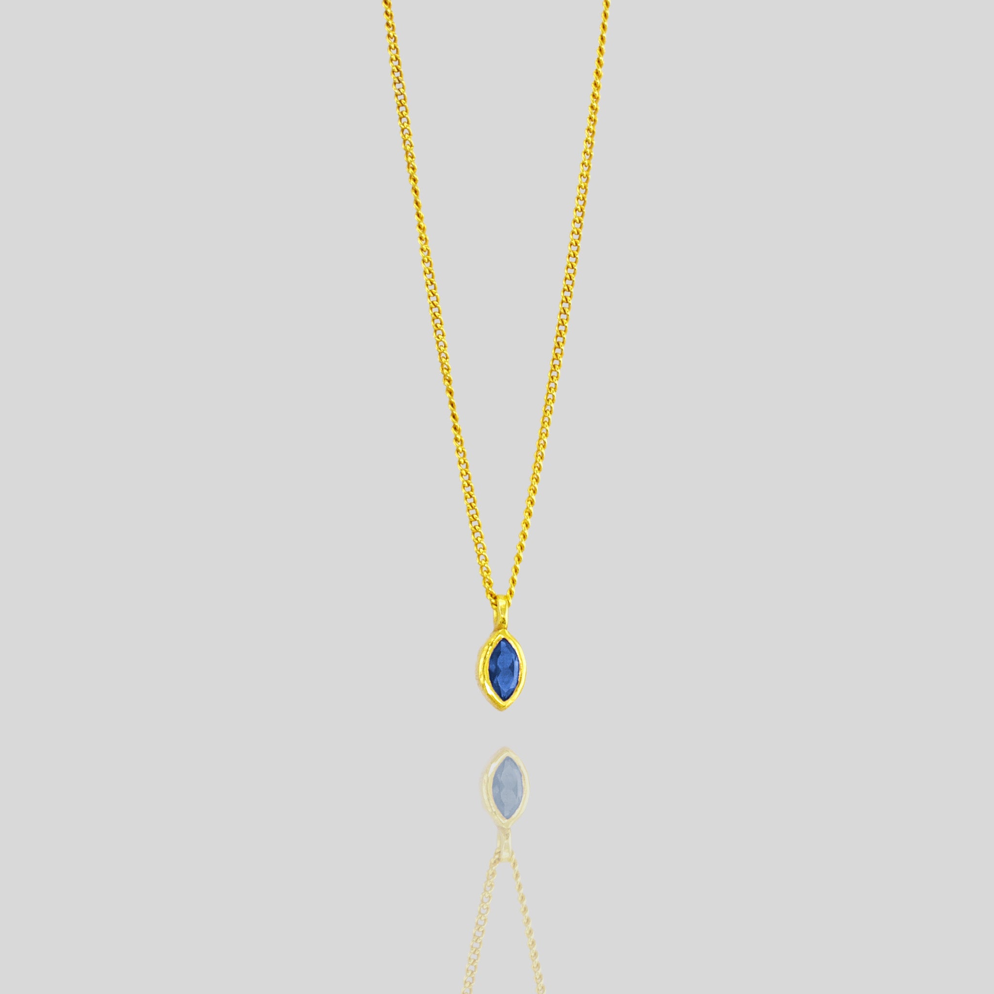 Elegant marquee gold pendant featuring a small, exquisite emerald, adding a delicate touch of vibrant green to enhance any outfit with sophistication.