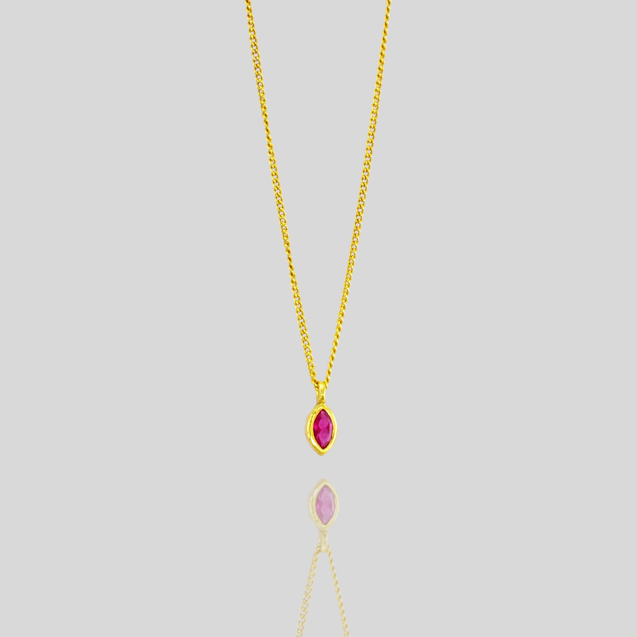 Elegant marquee gold pendant featuring a small, exquisite emerald, adding a delicate touch of vibrant green to enhance any outfit with sophistication.