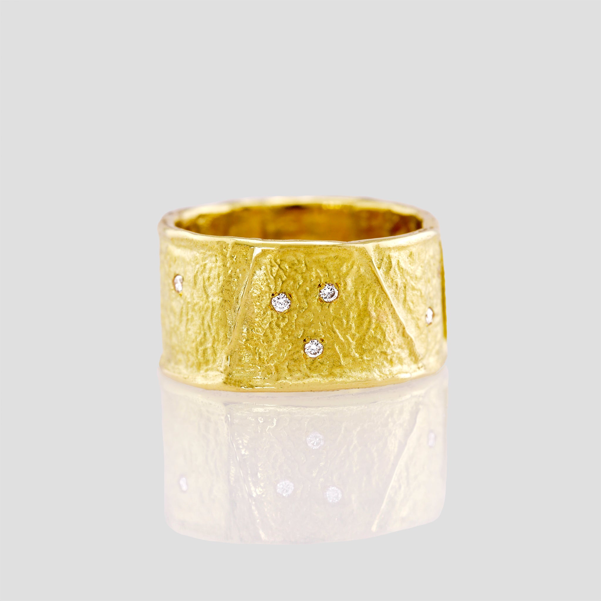 close up of A stunning 18k Yellow Gold Ring featuring a unique wrinkled texture inspired by ancient Egyptian artistry, elegantly adorned with tiny sparkling diamonds for a timeless charm.