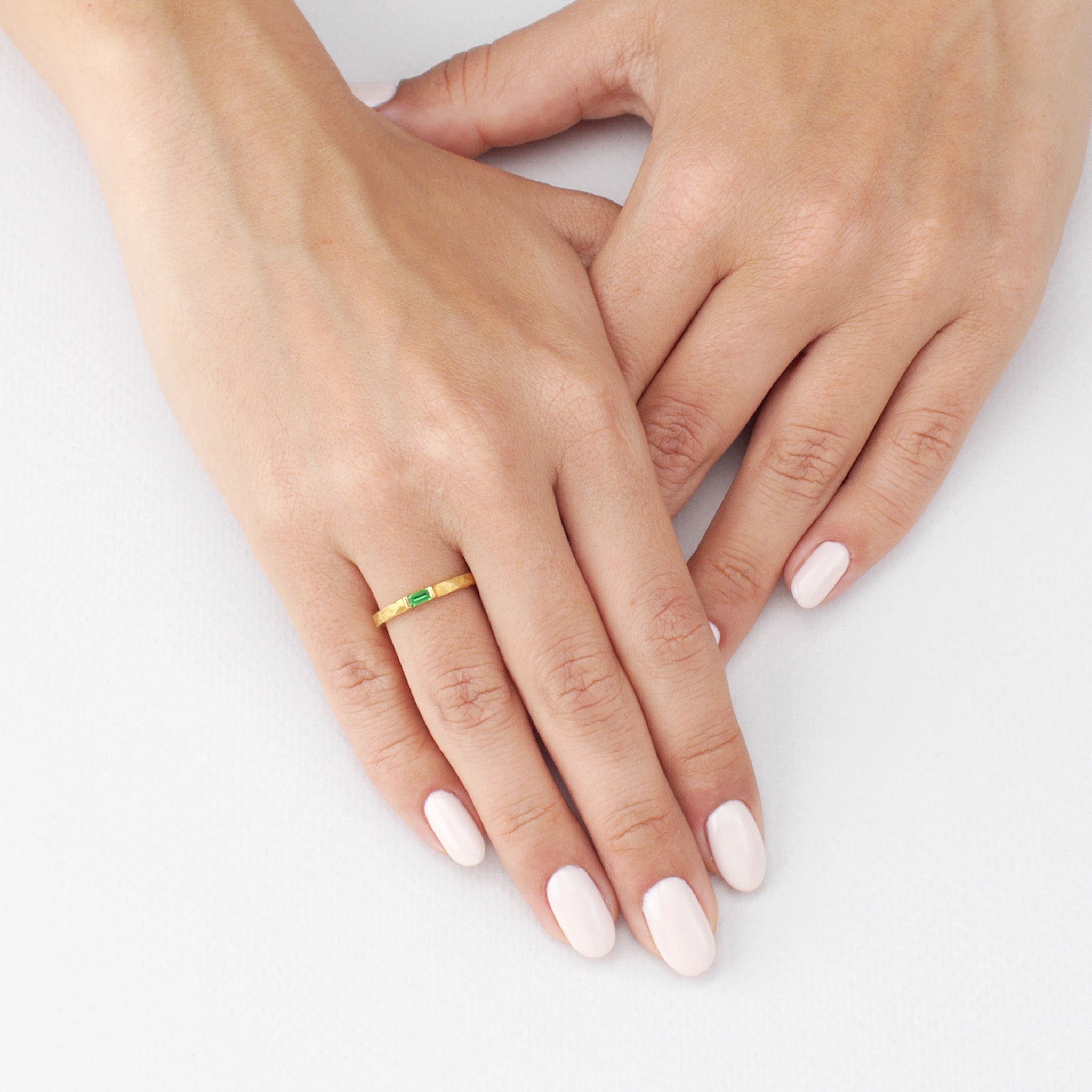 Model displaying a delicate handmade gold baguette ring with Emerald, showcasing the hand-hammered detail and the Emerald's radiance, adding timeless elegance to any look.