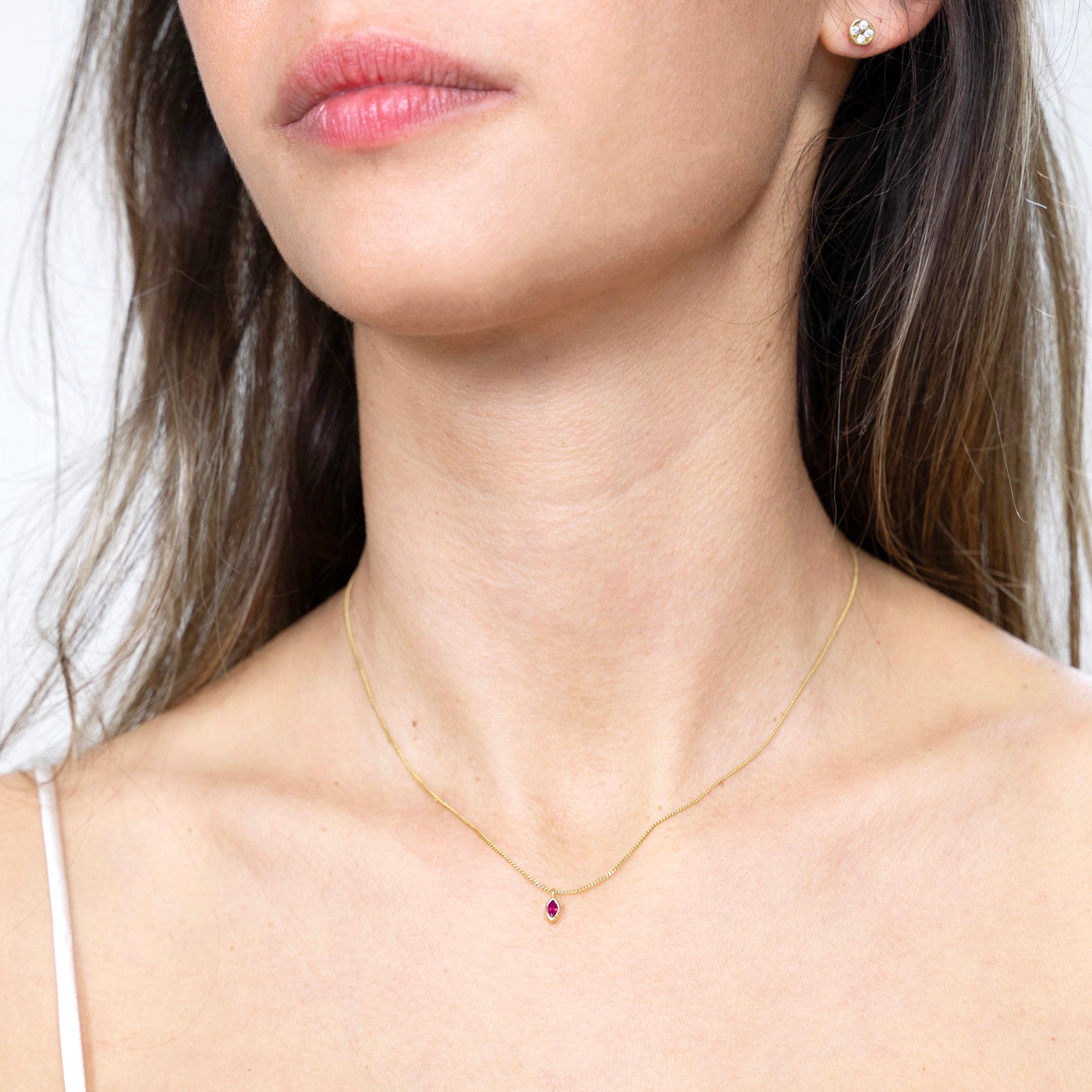 Model showcasing the elegant gold marquee pendant with a captivating emerald, infusing outfits with a touch of vibrant sophistication and symbolizing renewal, growth, and vitality.