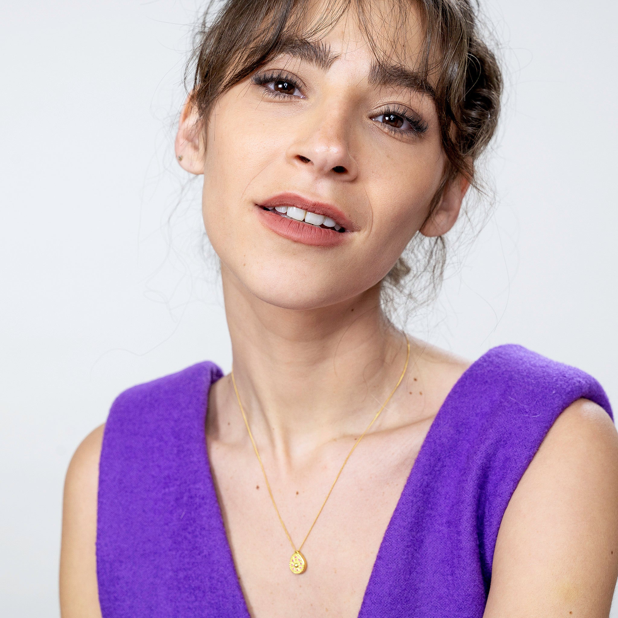 Model showcasing a unique gold sundial clock-shaped pendant, its edges embellished with tiny rubies, offering a luxurious and historical dimension to any ensemble.