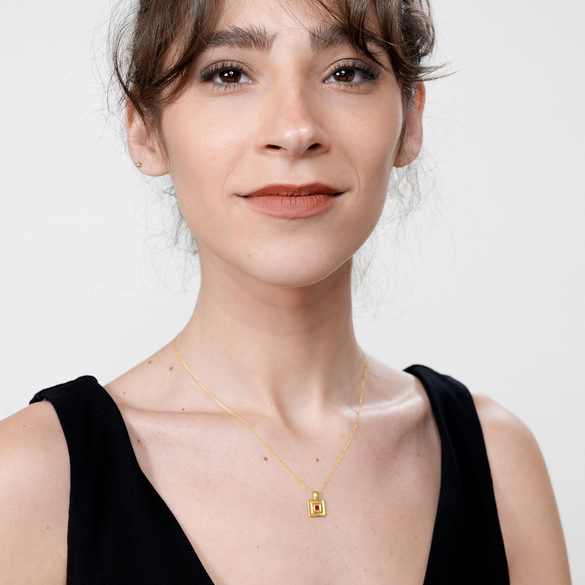 Model showcases the Pharaohs II handmade square gold pendant, centered with a square Ruby gemstone, a piece inspired by the regal adornments of Egypt's ancient rulers.