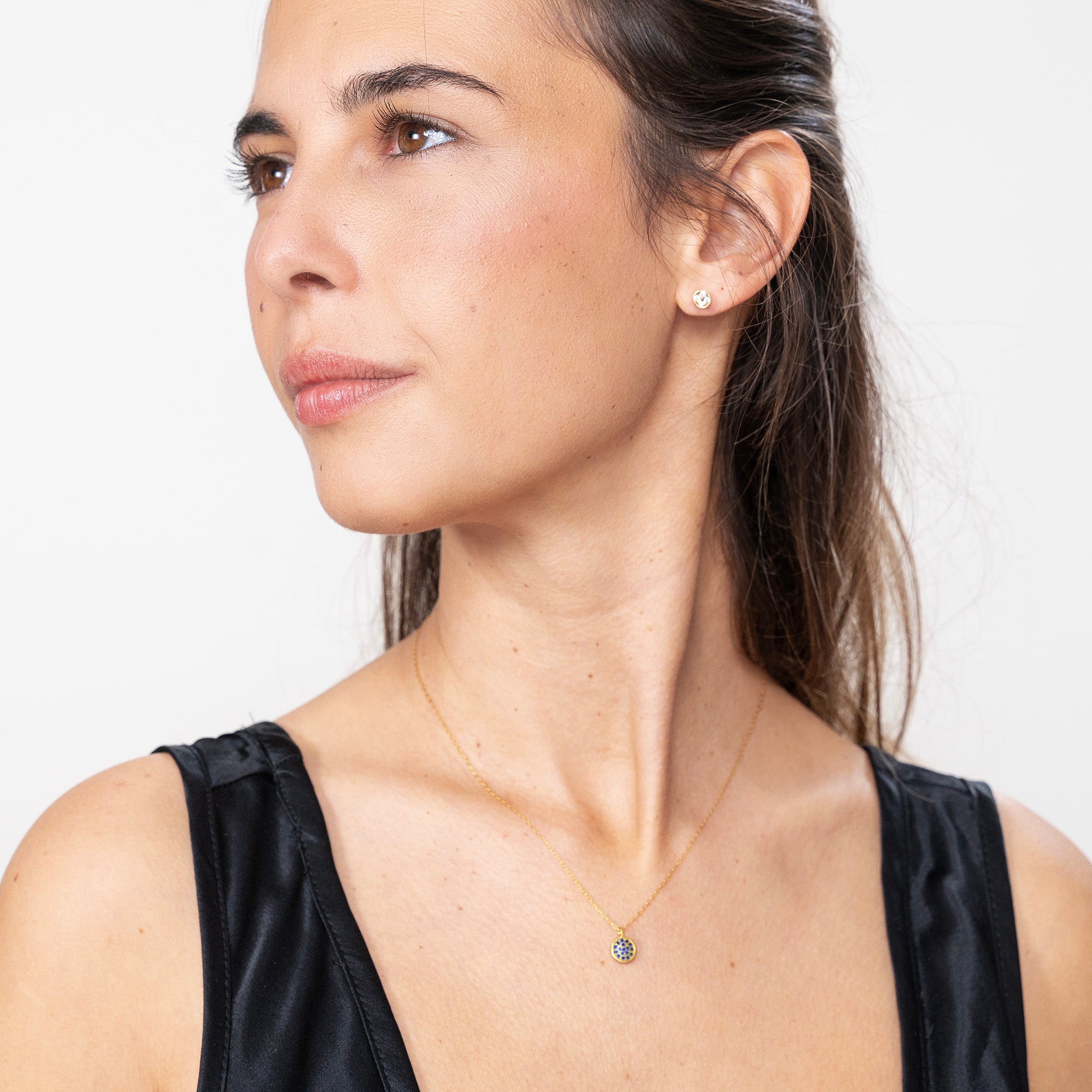Model beautifully wearing the Starlit gold pendant, with its gold plate accented by luminous Sapphires, each gleaming like a vivid star against the night's sky.