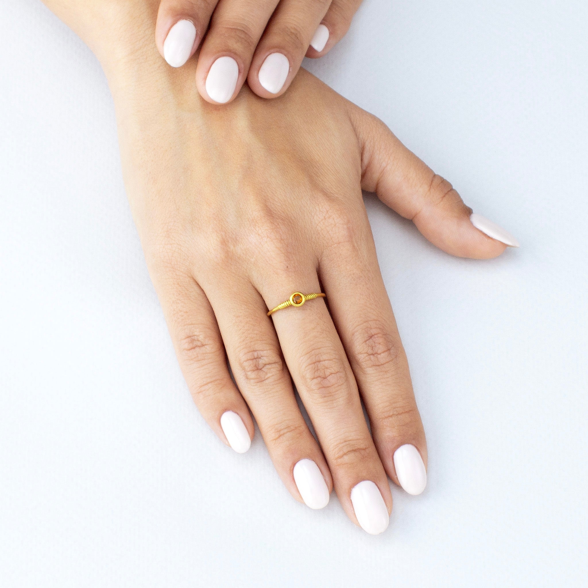 Model displaying a delicate gold coiled ring, featuring a Citrine gemstone, enhancing the finger with its poetic elegance.