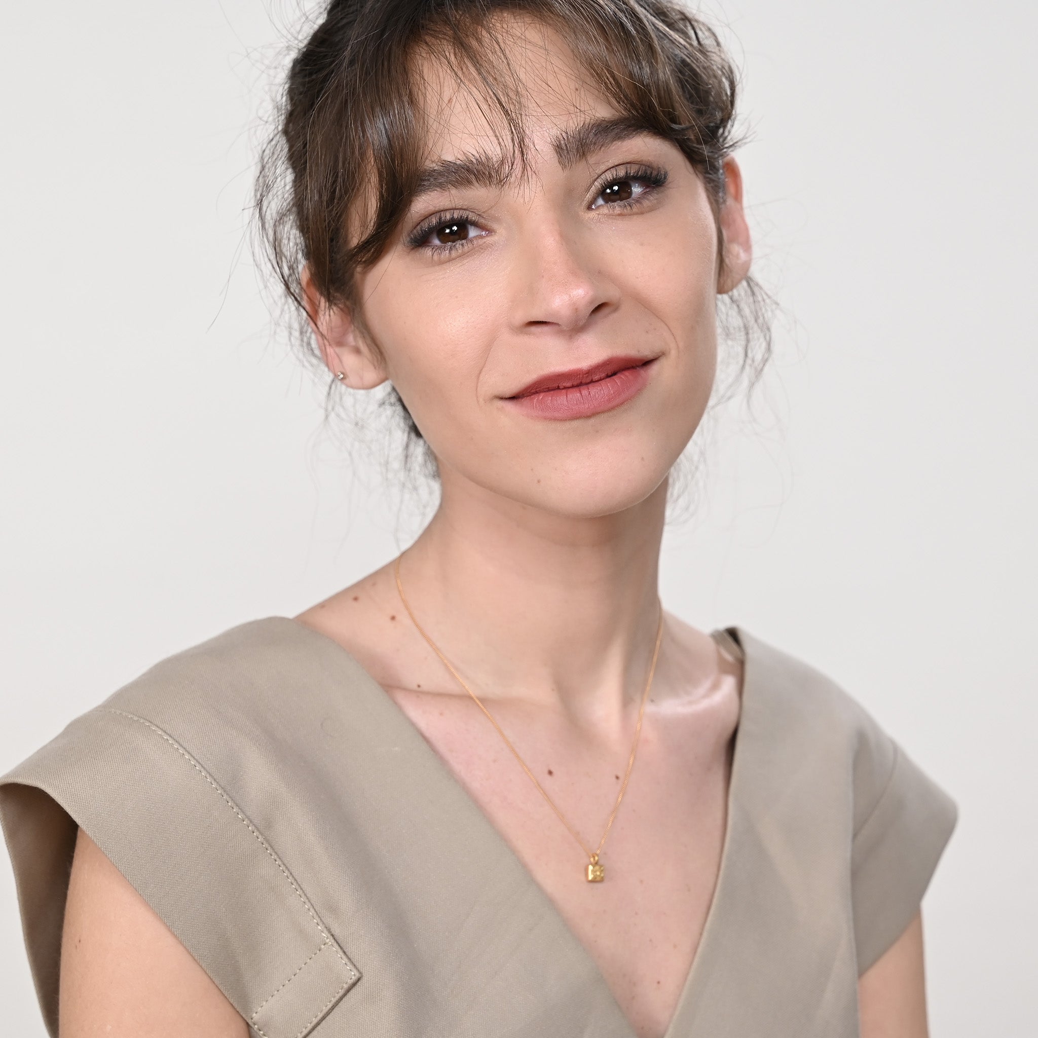 Model wearing a handmade square gold pendant, its central petite flower design making an elegant statement and adding a touch of sophistication.