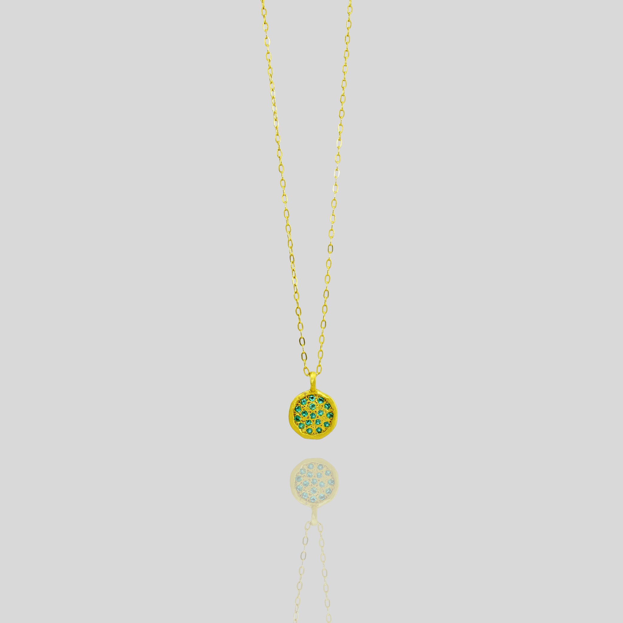Starlit gold pendant, meticulously crafted from Yellow Gold with a small gold plate embellished with scattered Emeralds, mirroring the enchanting allure of a starry night.