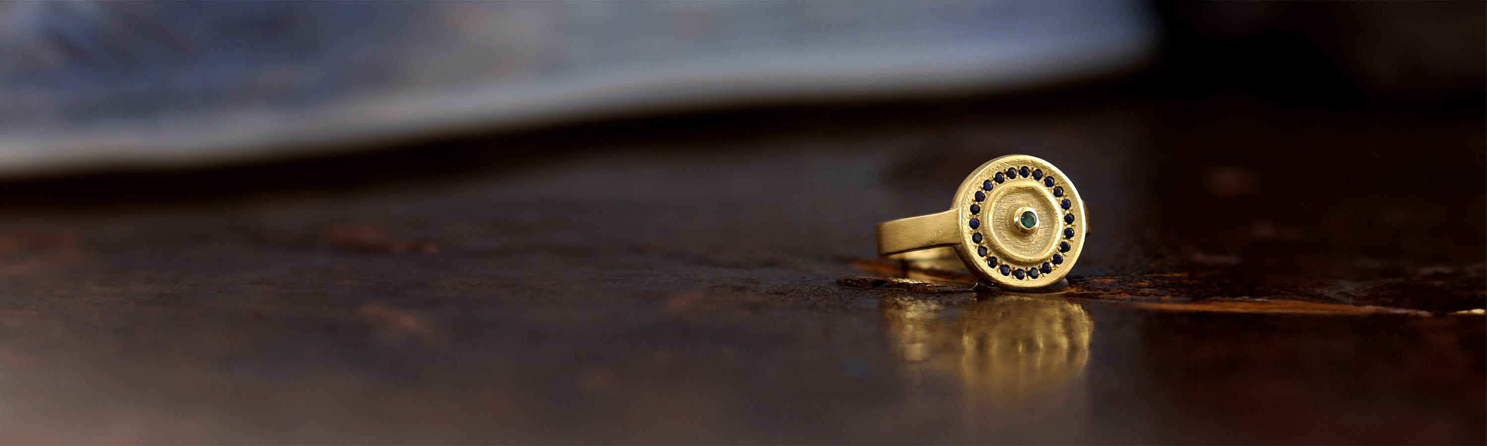 Yellow gold seal ring lying on a rustic surface with a dreamy background
