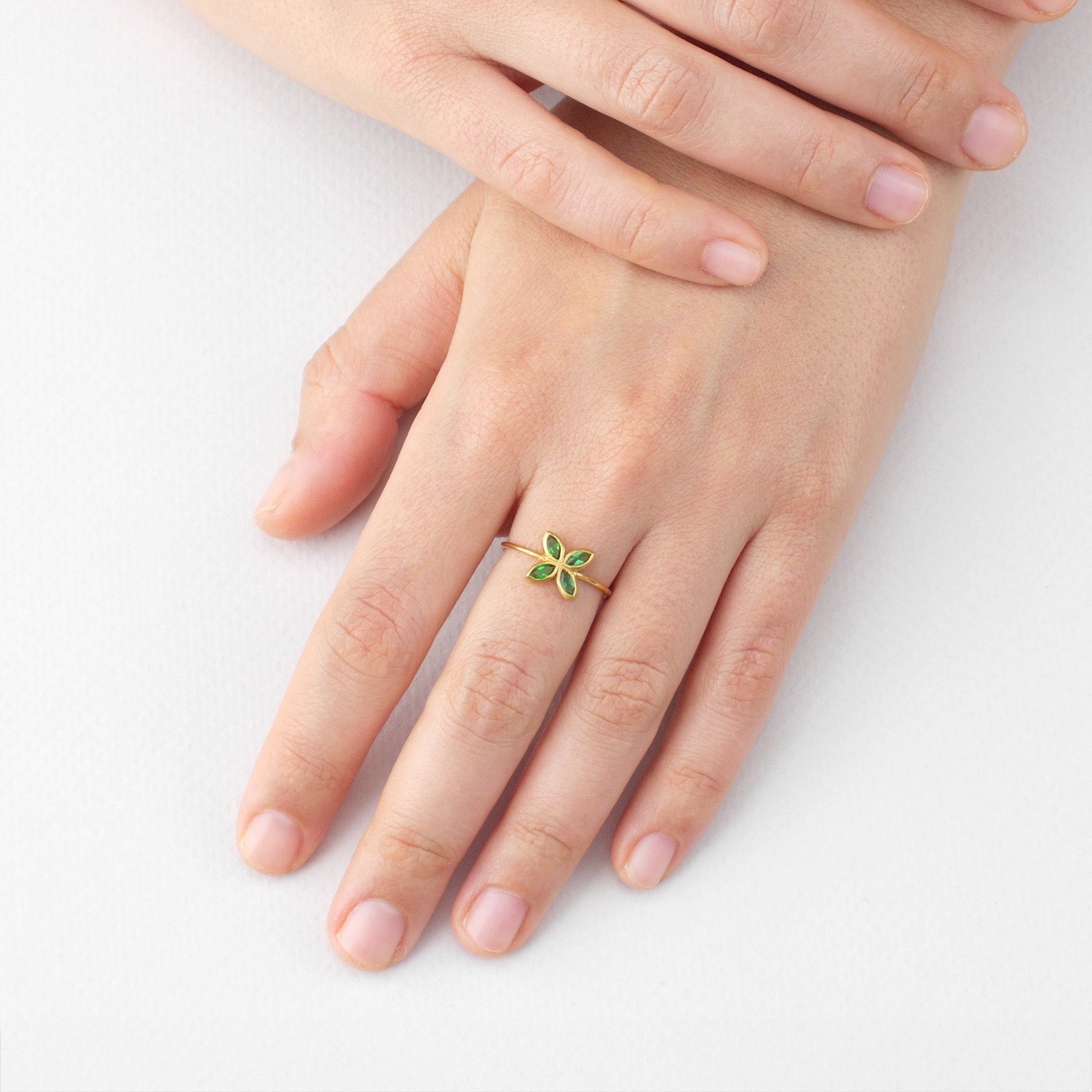 Model displaying a Delicate Gold ring with Emerald marquise in a flower-shaped design. Radiant and cheerful addition to any collection.