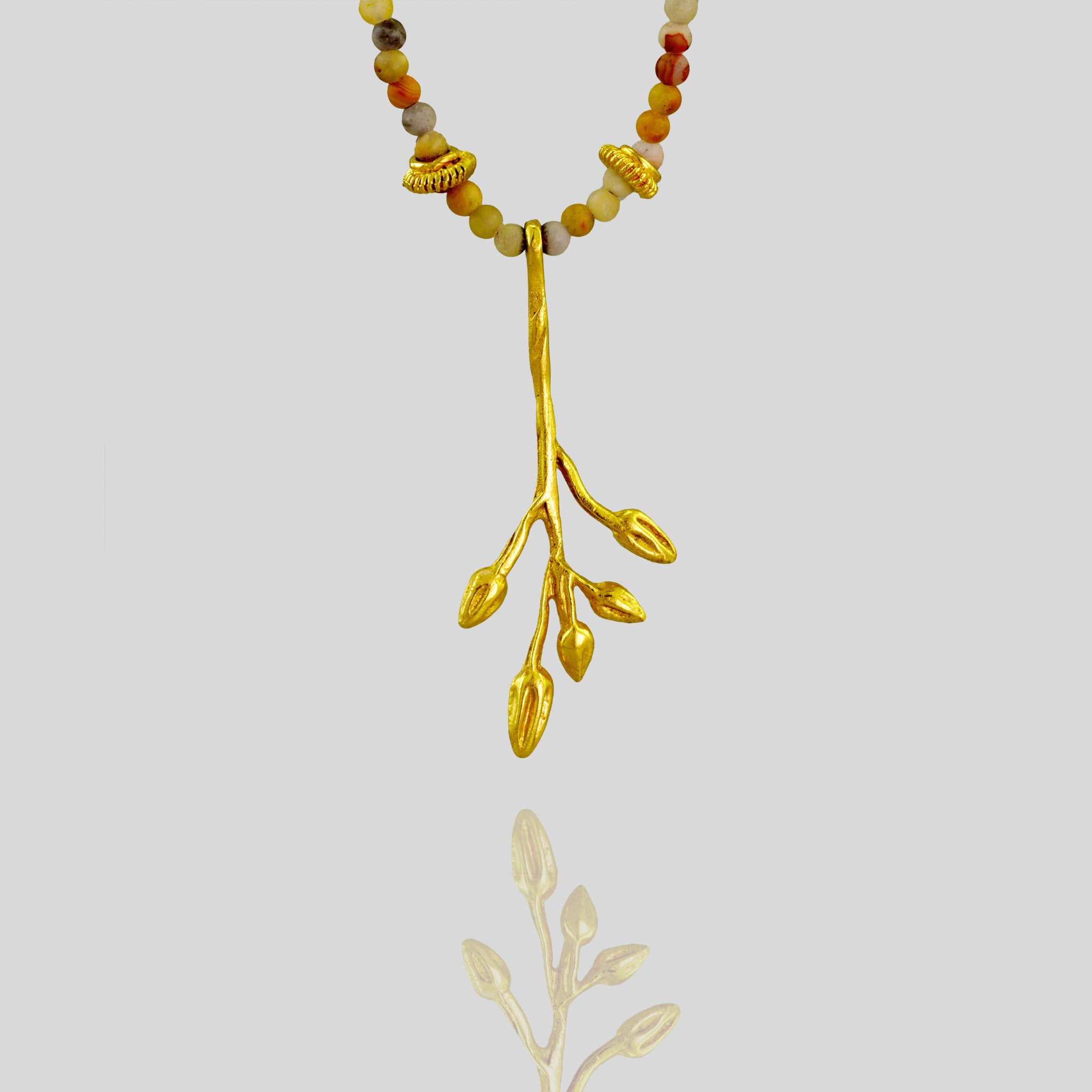 Detail of a Delicate yellow gold pendant designed to resemble a branch with dried seed pods, adorned with Jasper stones and gold elements for a vibrant and natural look.