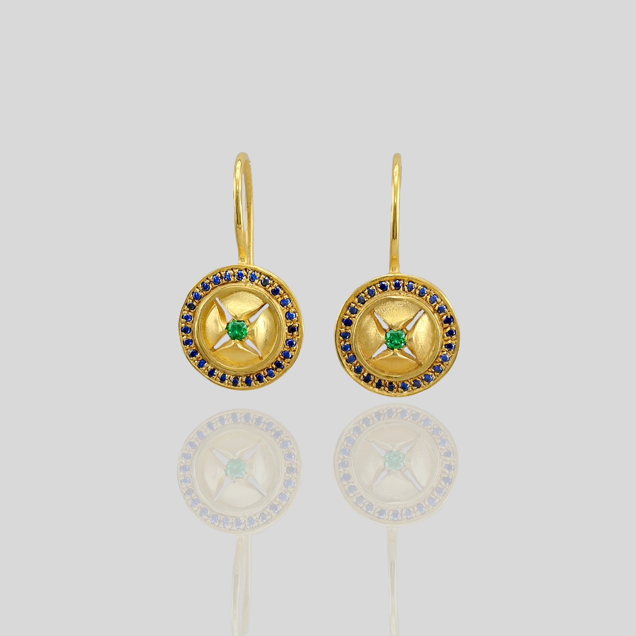 close up of Yellow Gold Drop Earrings with Emerald star motif and sparkling Sapphires, exuding sophistication and timeless elegance.