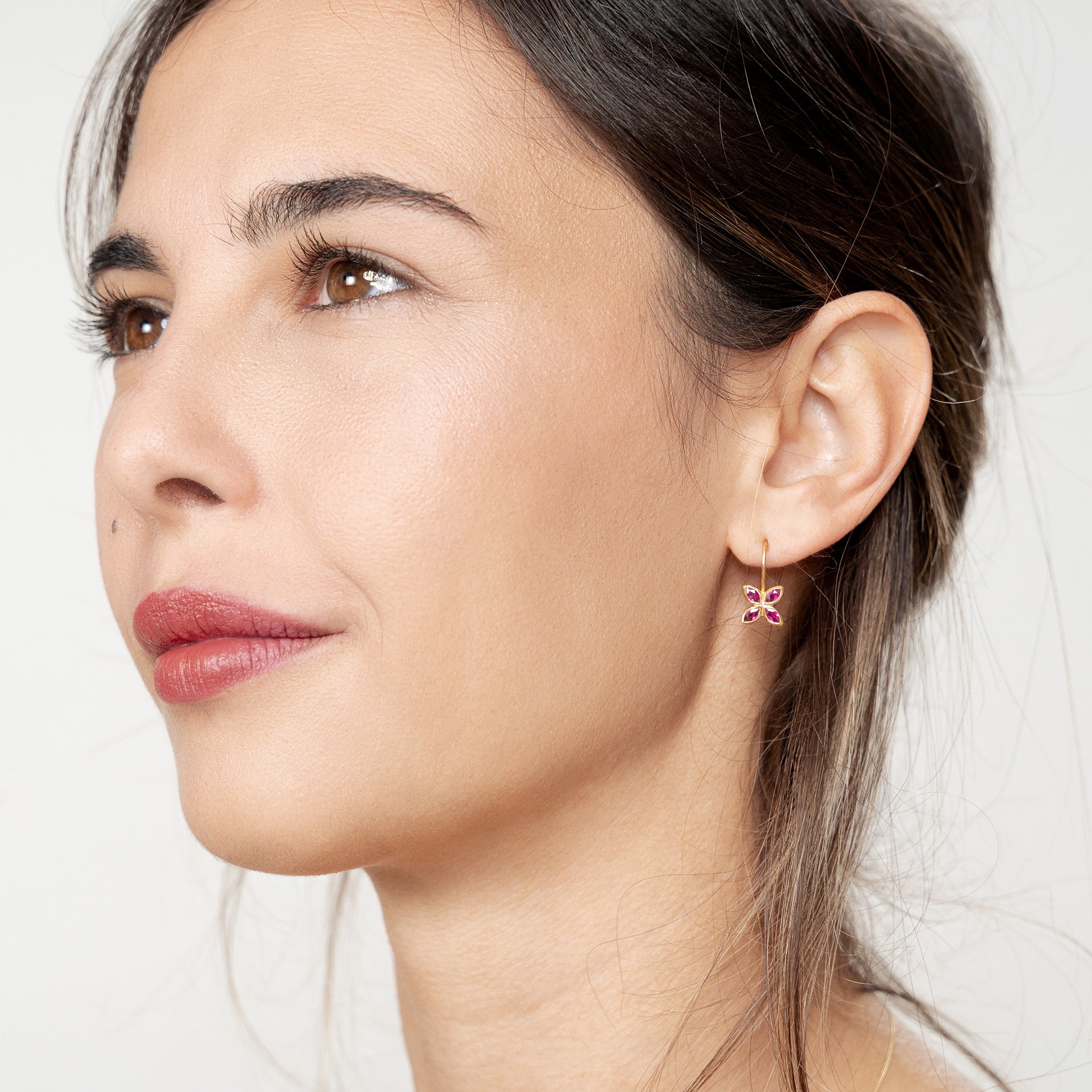 Model wearing Dazzling Ruby flower earrings, crafted from 4 marquise gemstones. Lightweight, colorful and vibrant.