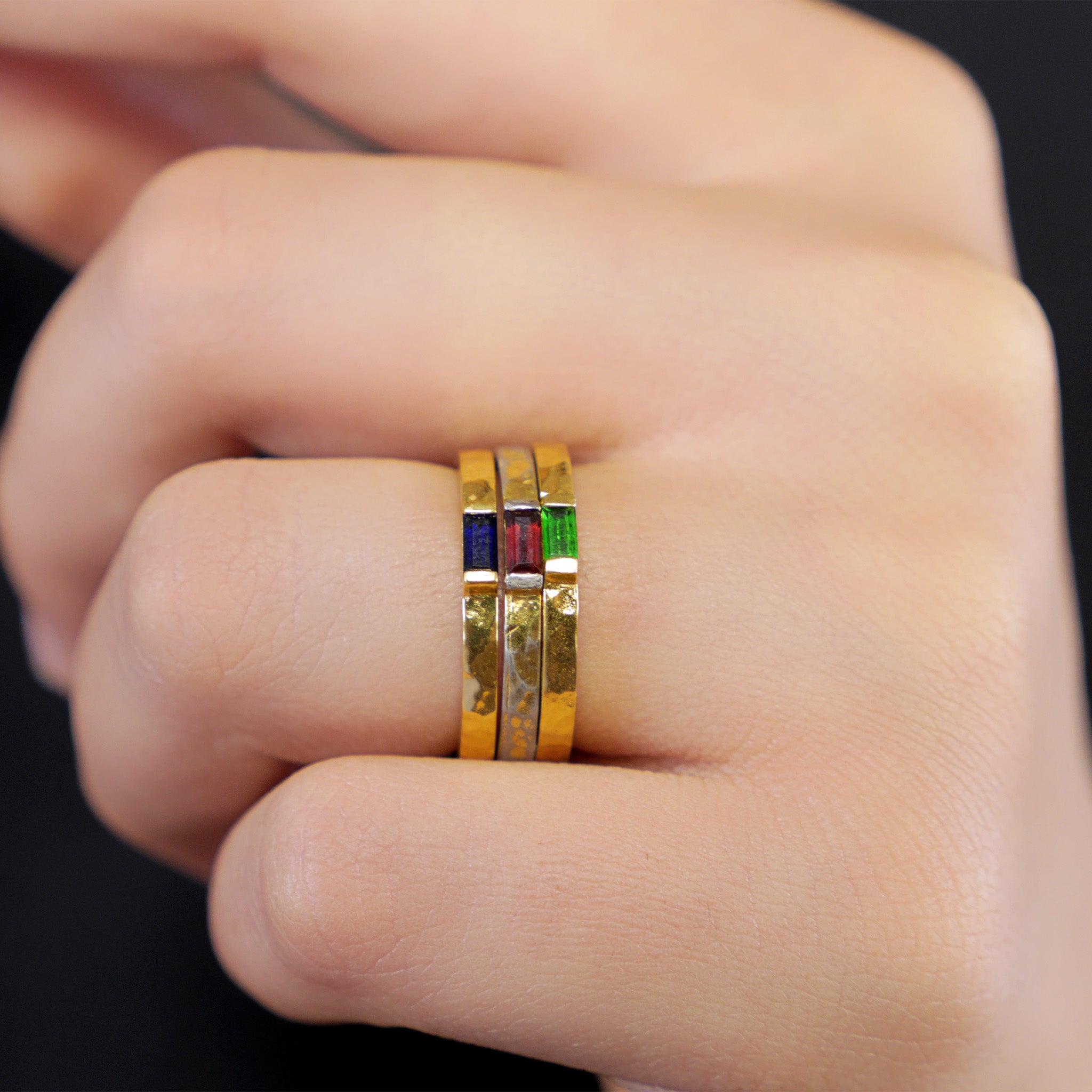 Model displaying three delicate handmade gold baguette rings with Ruby,  Emerald, and Sapphire.