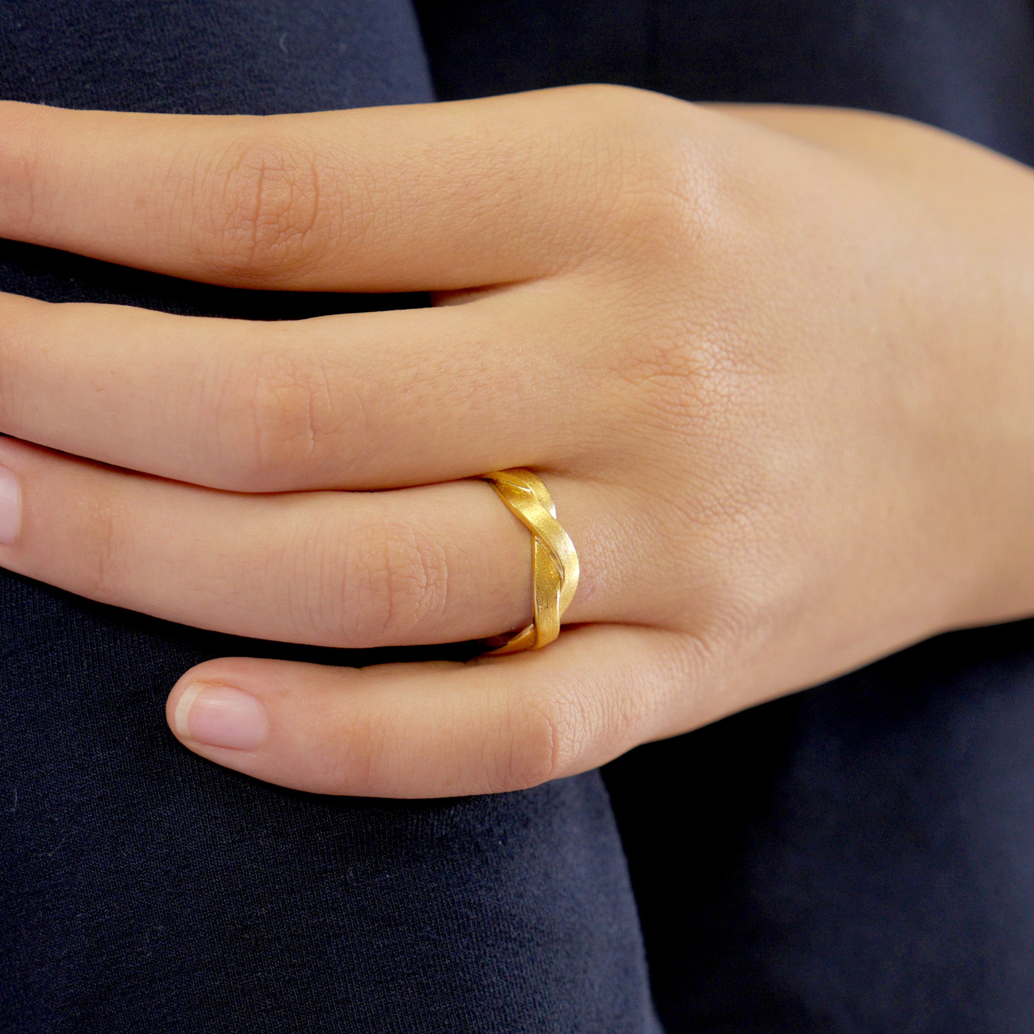 Close up on a model of our Hand-crafted ring made from Yellow Gold braids, offering an elegant and timeless touch to any attire. Intricately designed with subtle sophistication