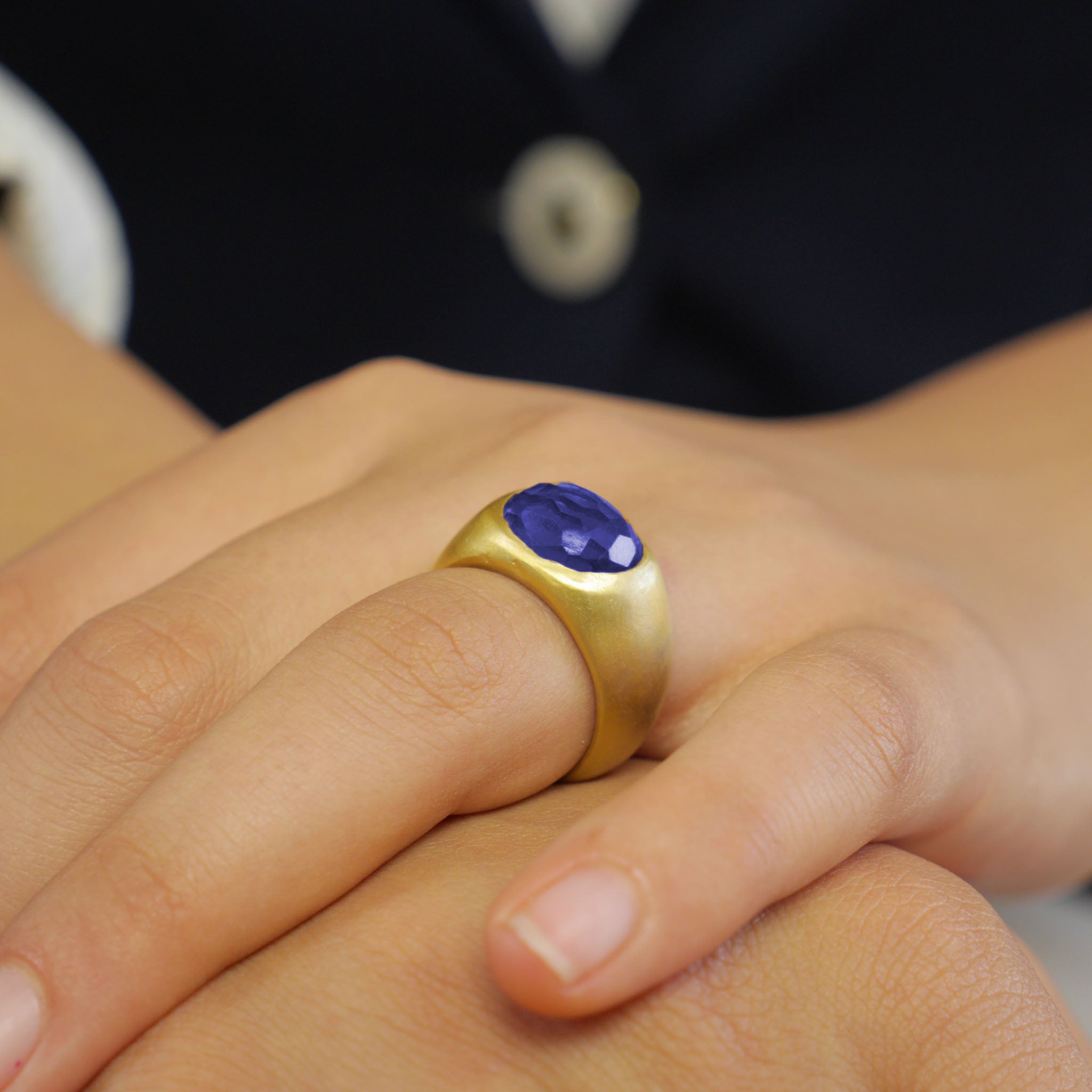 A timeless gold oval ring adorned with a captivating Sapphire gemstone on a model's finger. This classic piece exudes traditional elegance and is beloved for its enduring appeal.