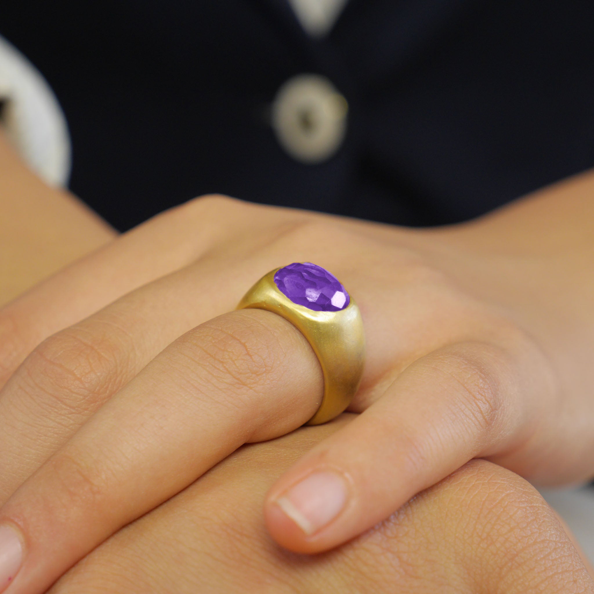 A timeless 18k Gold oval ring adorned with a captivating amethyst gemstone on a model. This classic piece exudes traditional elegance and is beloved for its enduring appeal.