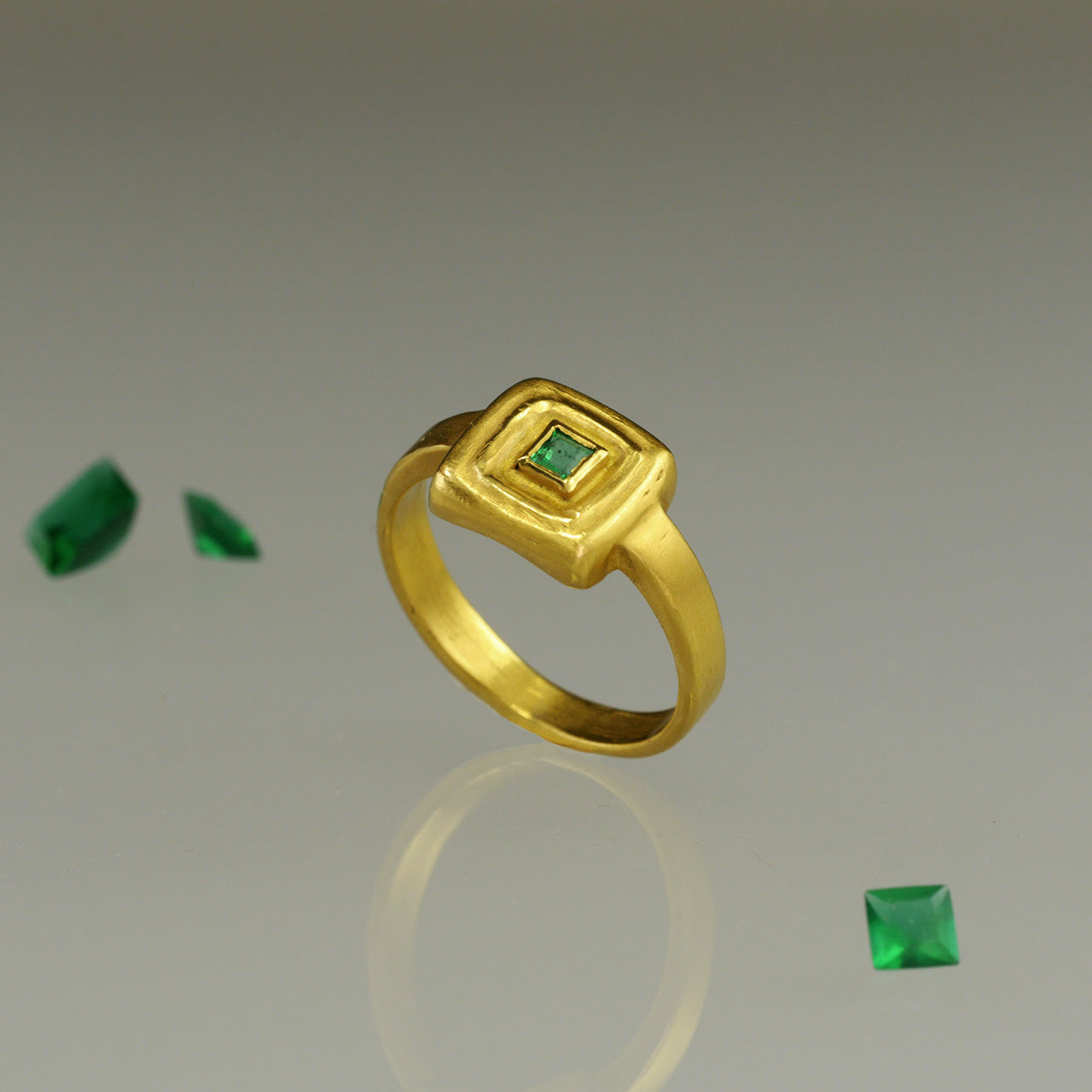 Top view of Handcrafted 18k Gold ring featuring a square Emerald set atop a square surface, evoking the ancient Egyptian era's golden jewelry of the Pharaohs.