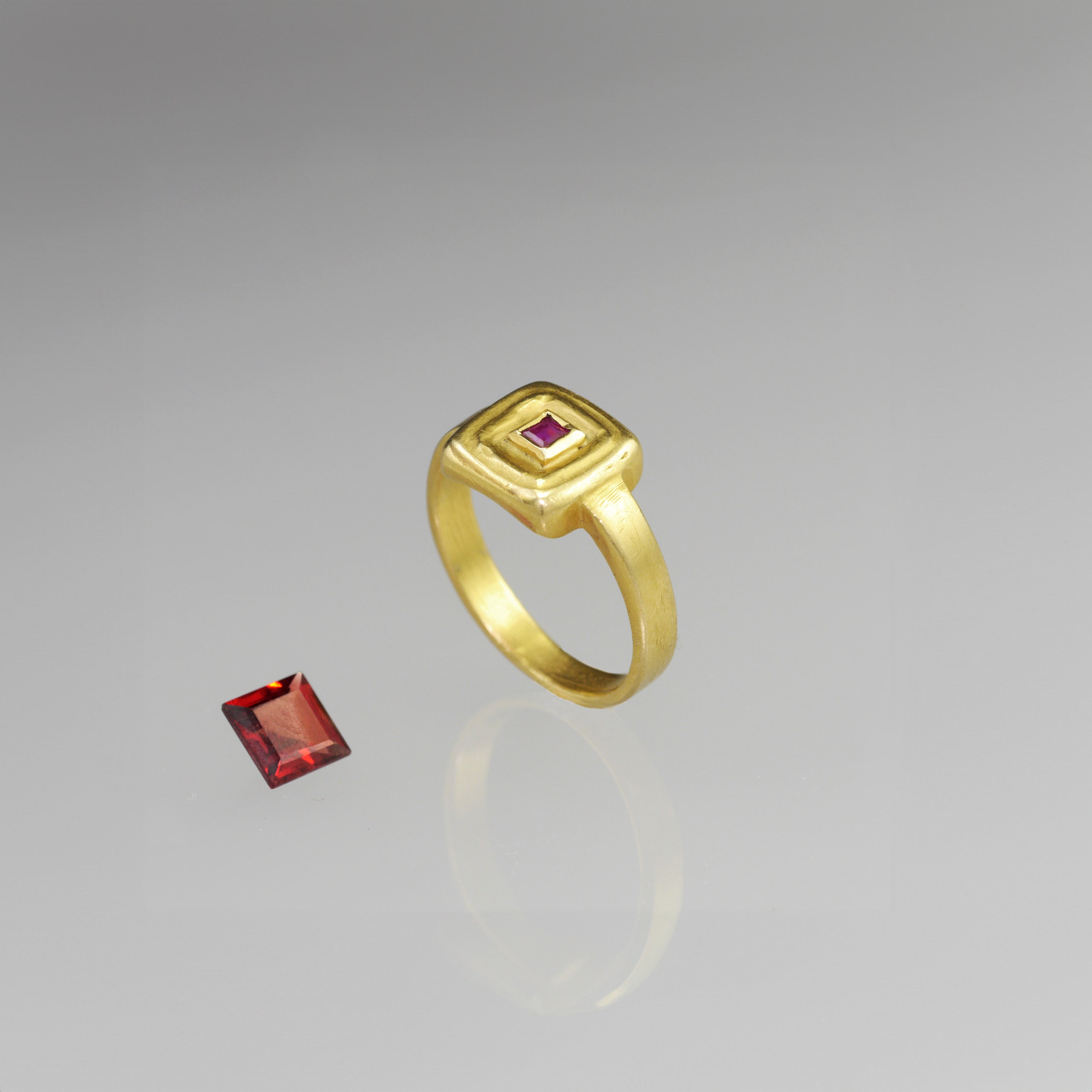 Top view of Handcrafted 18k Gold ring featuring a square Ruby set atop a square surface, evoking the ancient Egyptian era's golden jewelry of the Pharaohs.