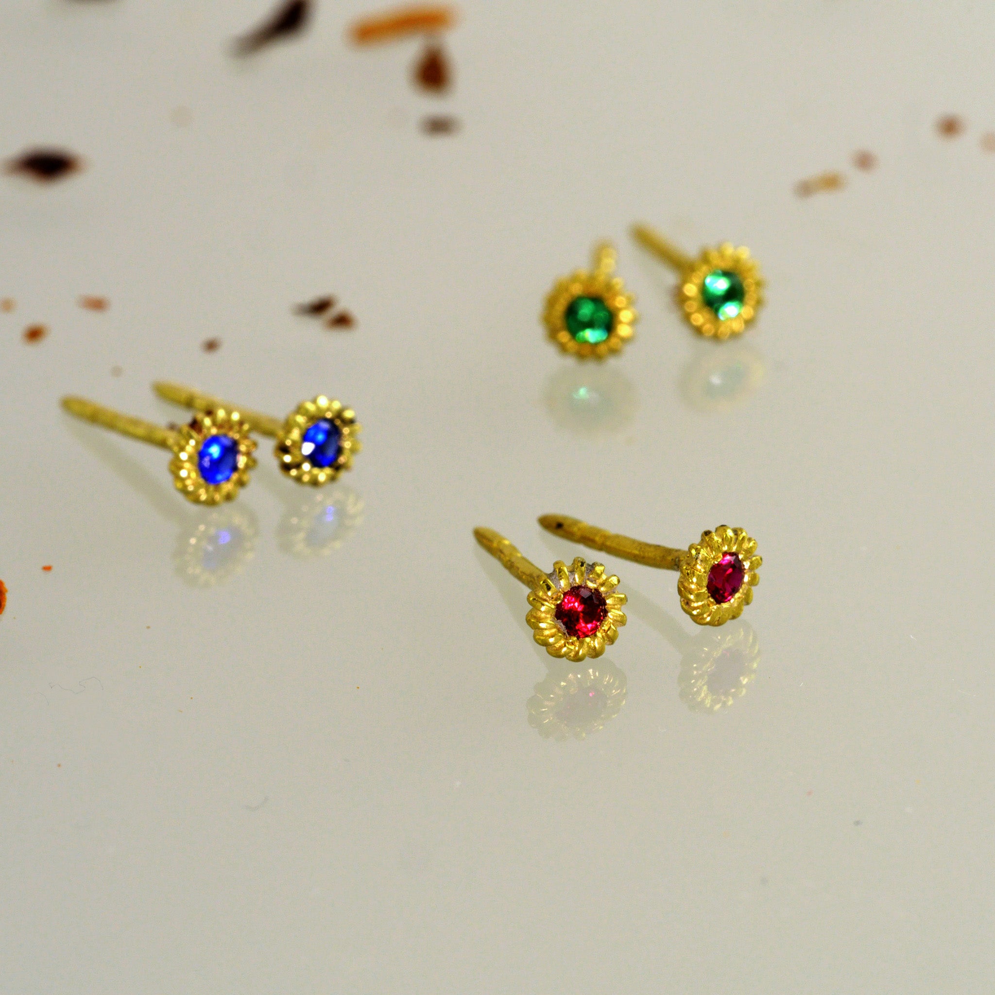 Scattered Tiny, coiled 18k gold studs with Ruby, Sapphire and Emerald.