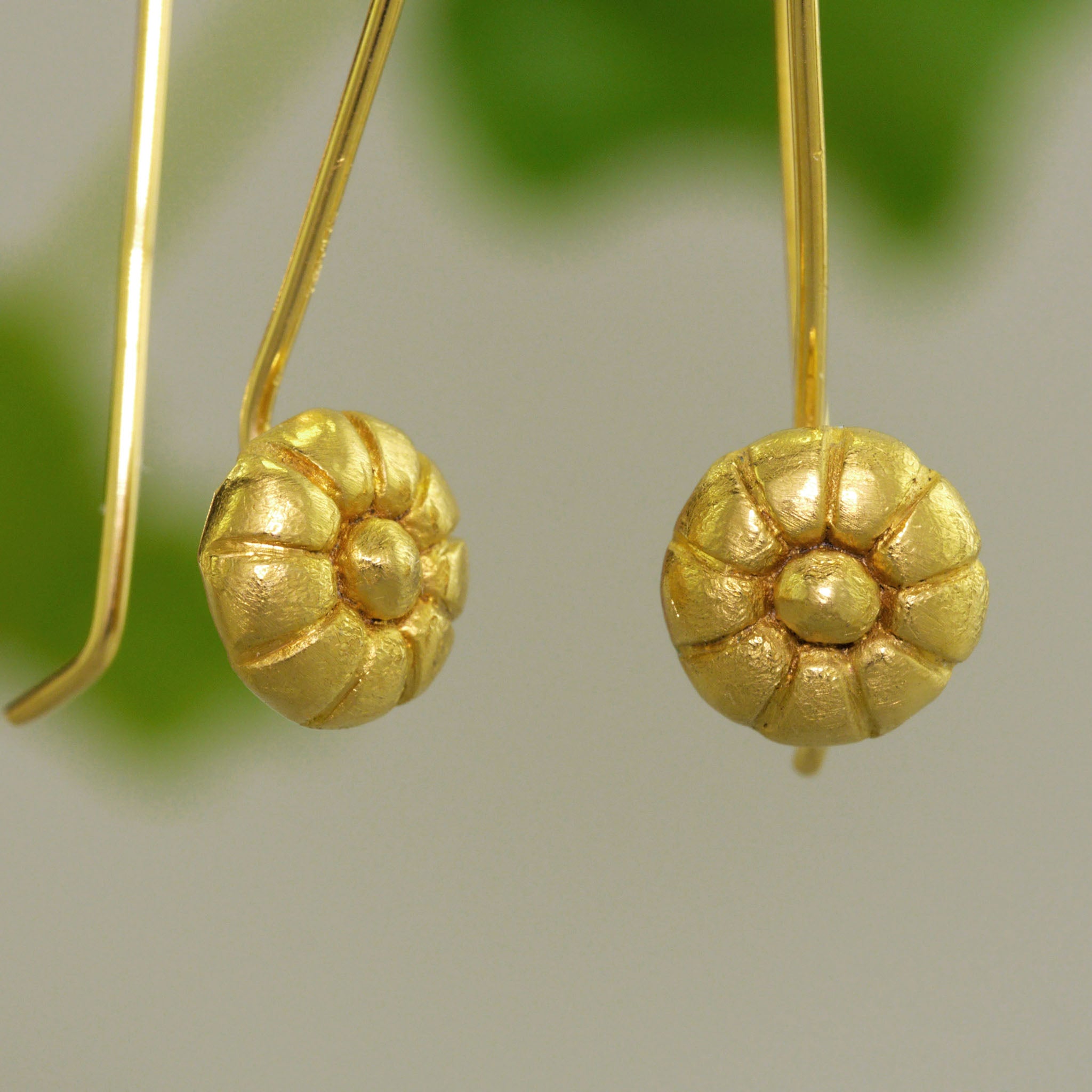 Close up of Mallow Fruit-inspired Gold Drop Earrings with natural green background.