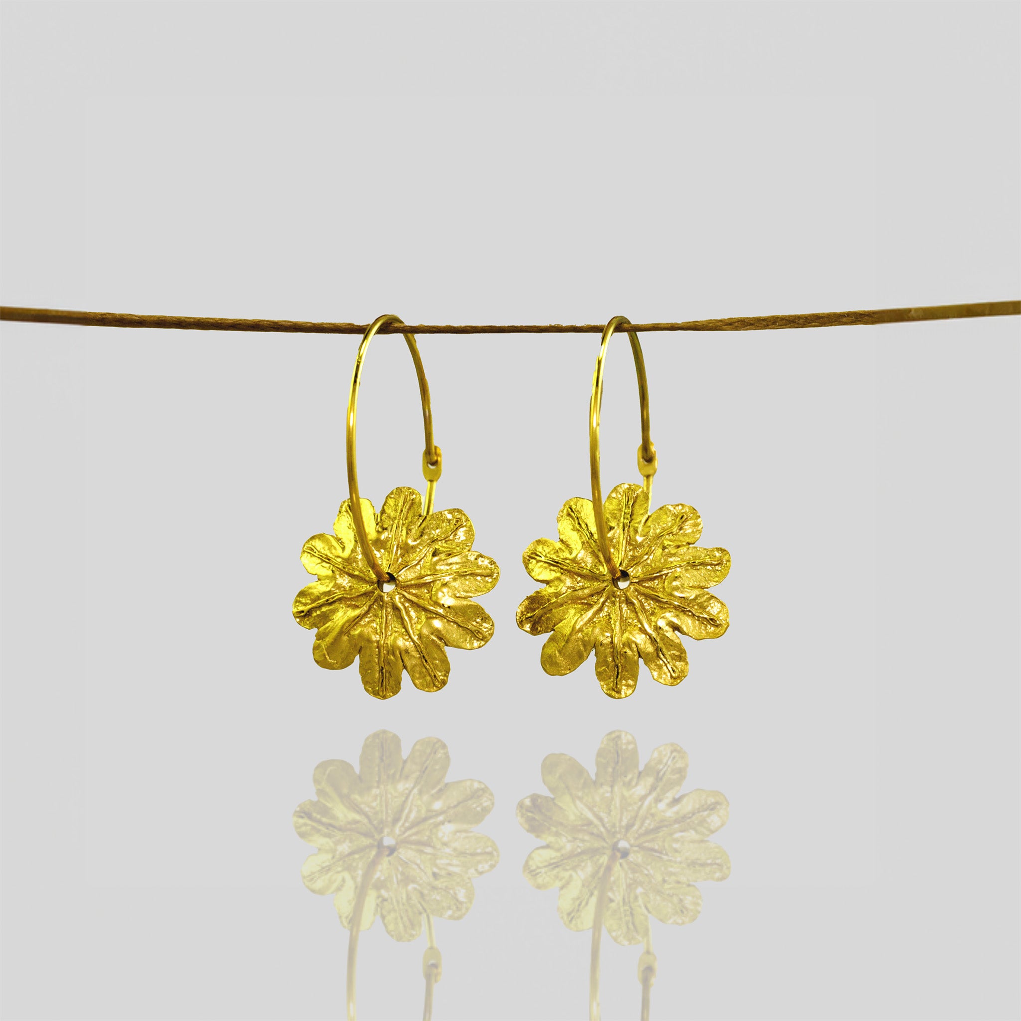 Close up of Gold Poppy Flower Hoop Earrings with Captivating Beauty hanging from a natural thread.