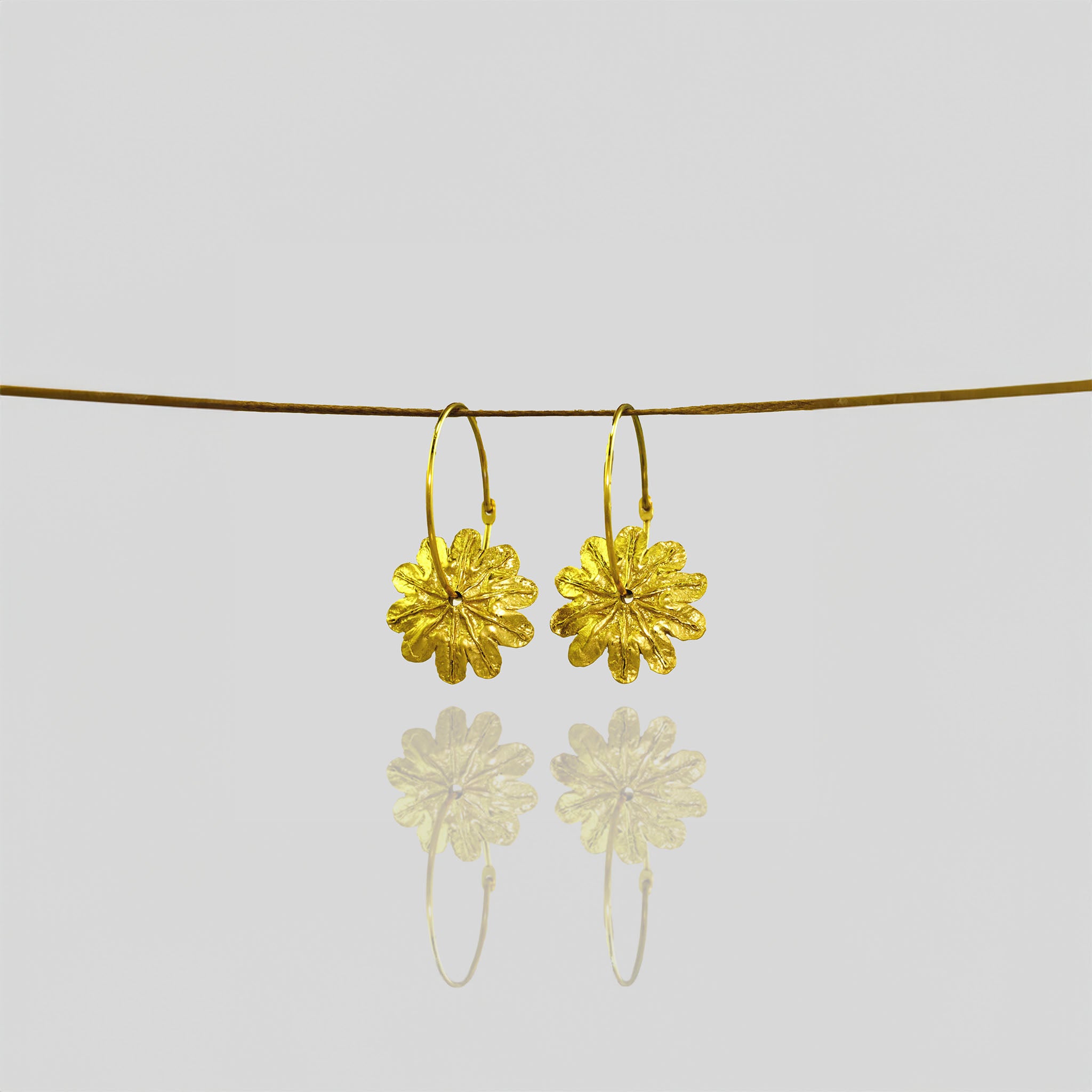 18k Gold Poppy Flower Hoop Earrings with Captivating Beauty hanging from a natural thread.
