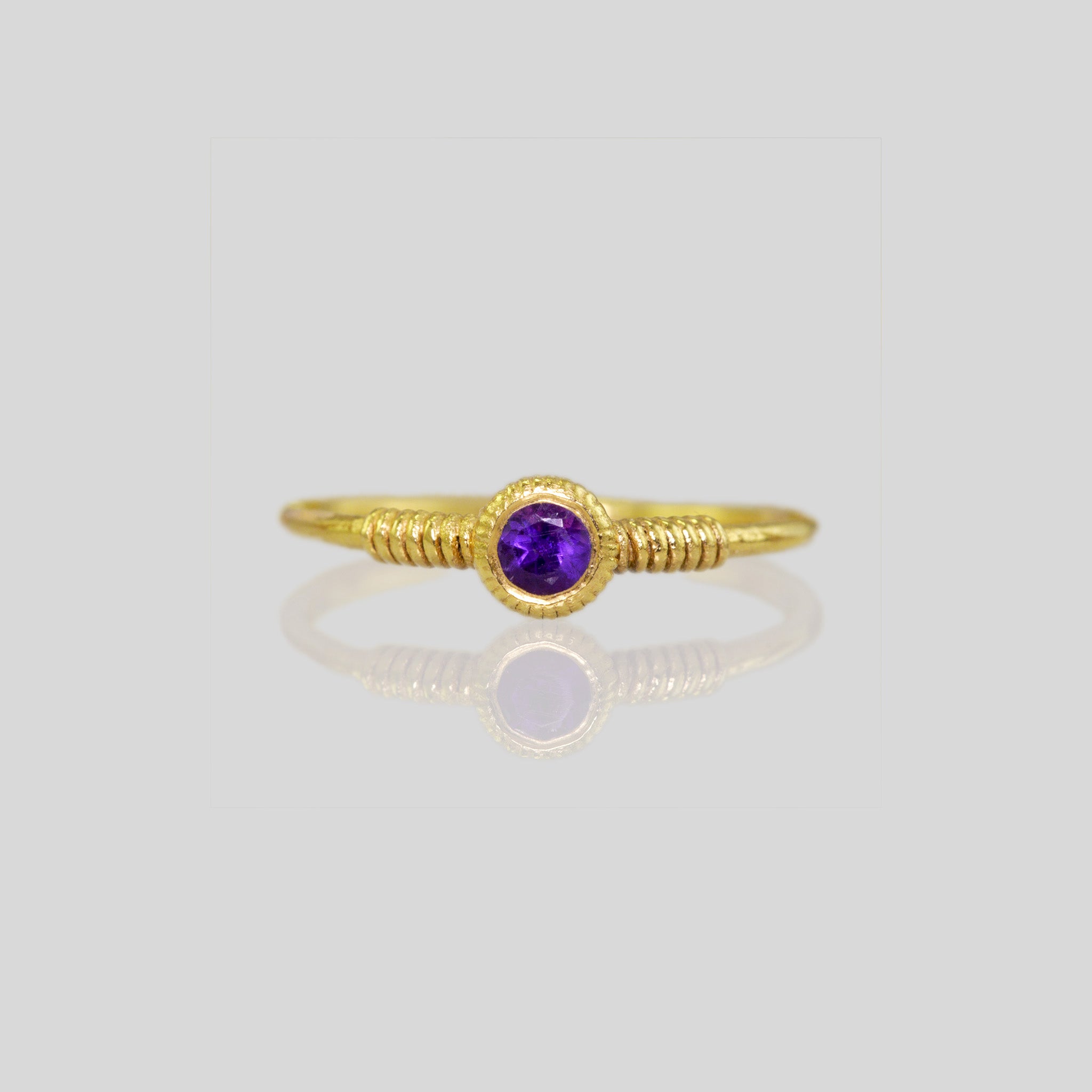Front view of delicate gold coiled ring adorned with Amethyst gemstone, highlighting its graceful coiled design.