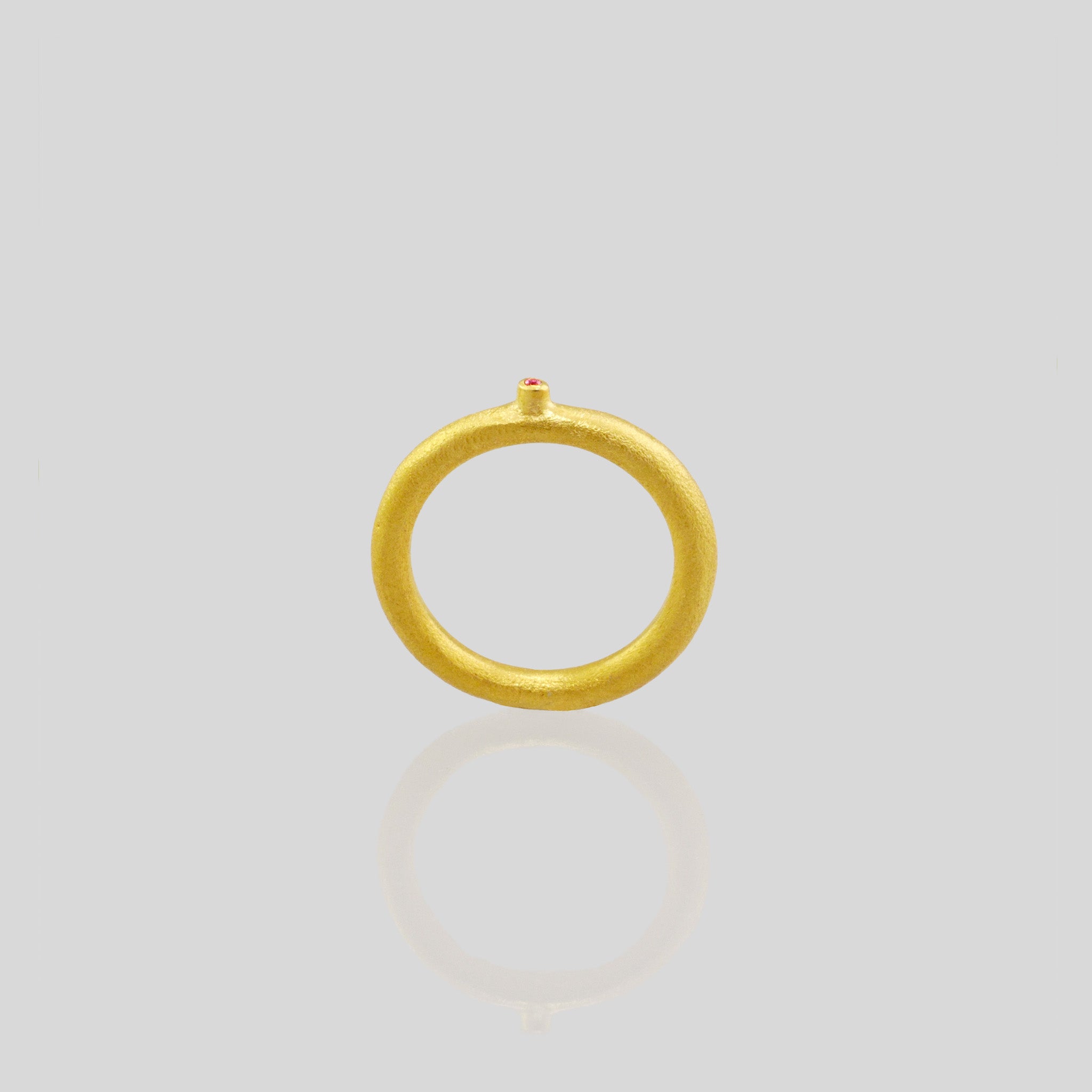 Side view of an 18k Gold Ring with a round matte finish and a slender tentacle extending from it, adorned with an inlaid ruby stone. Inspired by a small slug observed on the porch, the design exudes a delicate, natural charm with a playful touch.
