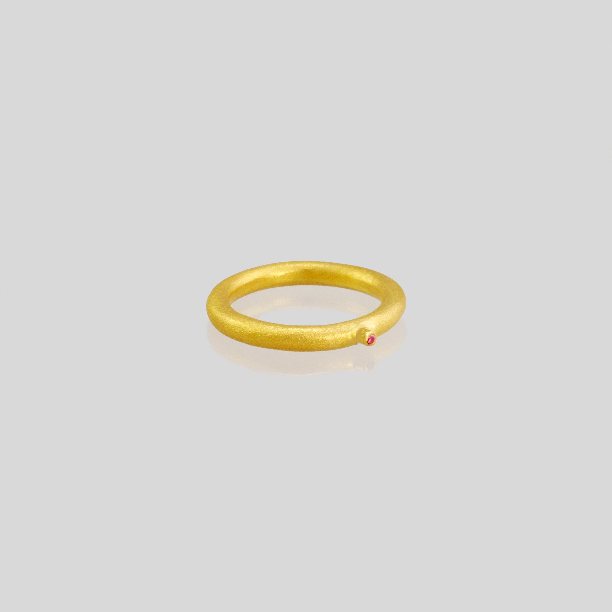 18k Gold Ring with a round matte finish and a slender tentacle extending from it, adorned with an inlaid ruby stone. Inspired by a small slug observed on the porch, the design exudes a delicate, natural charm with a playful touch.