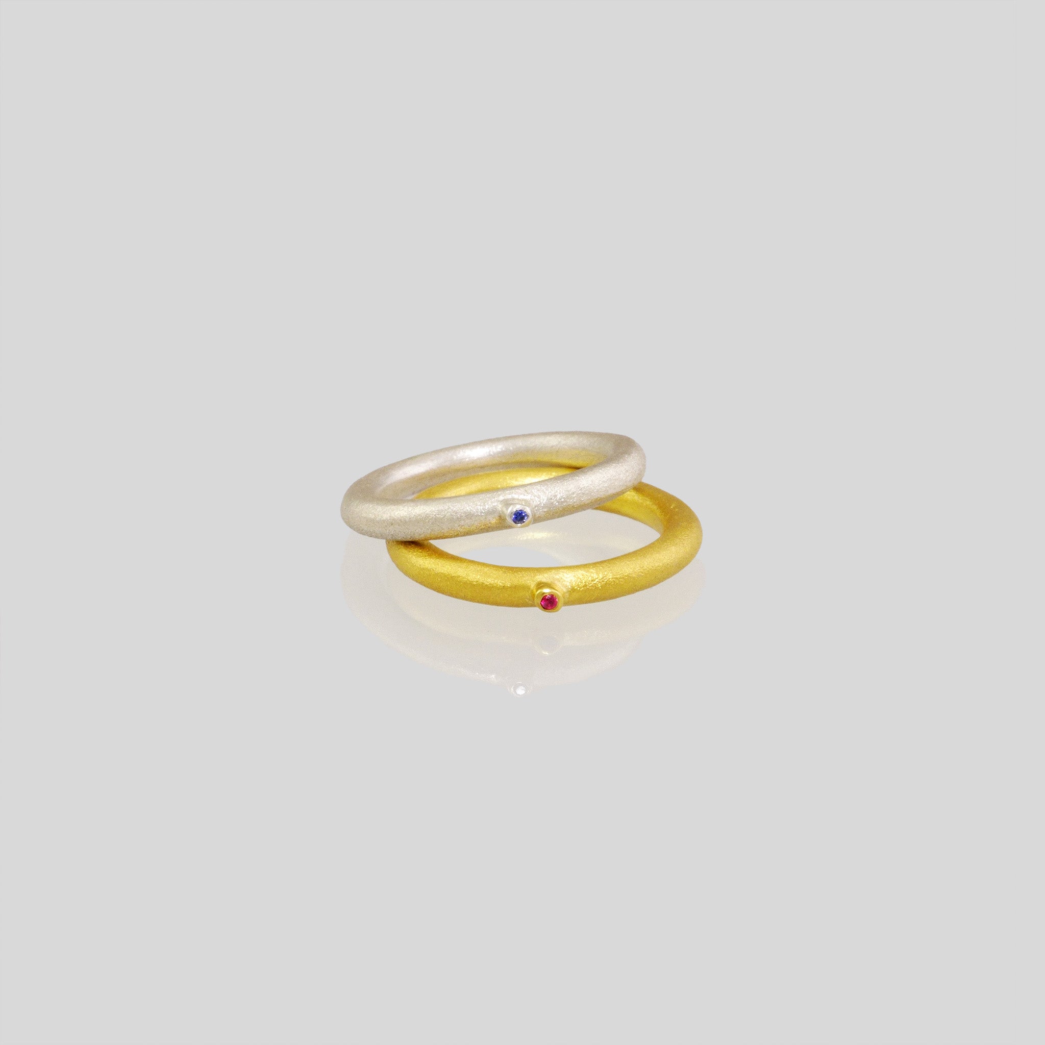18k (White\Yellow) Gold Rings with a round matte finish and a slender tentacle extending from it, adorned with an inlaid ruby stone. Inspired by a small slug observed on the porch, the design exudes a delicate, natural charm with a playful touch.