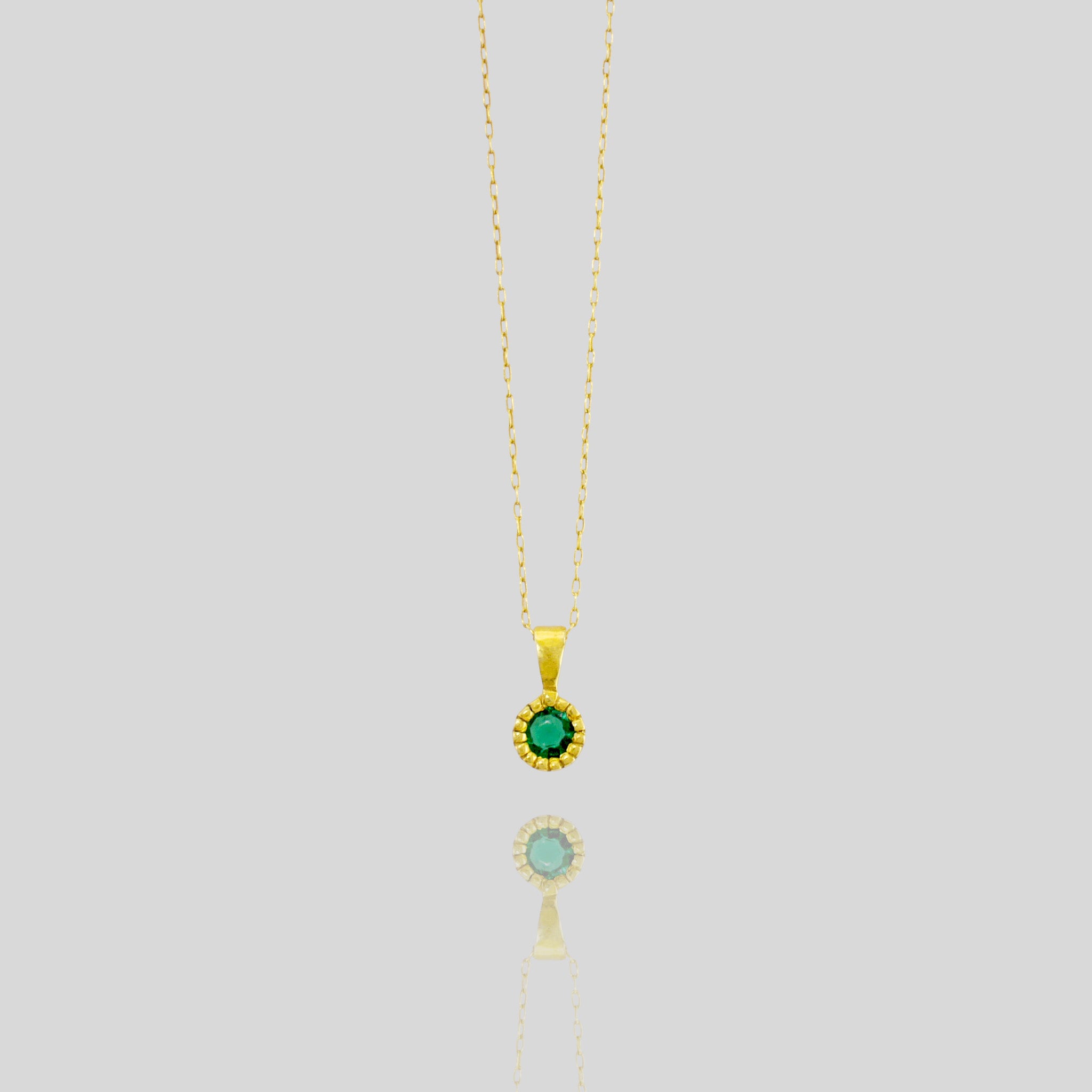 Elegant round gold pendant with embroidered texture and central Emerald, exuding classic sophistication.