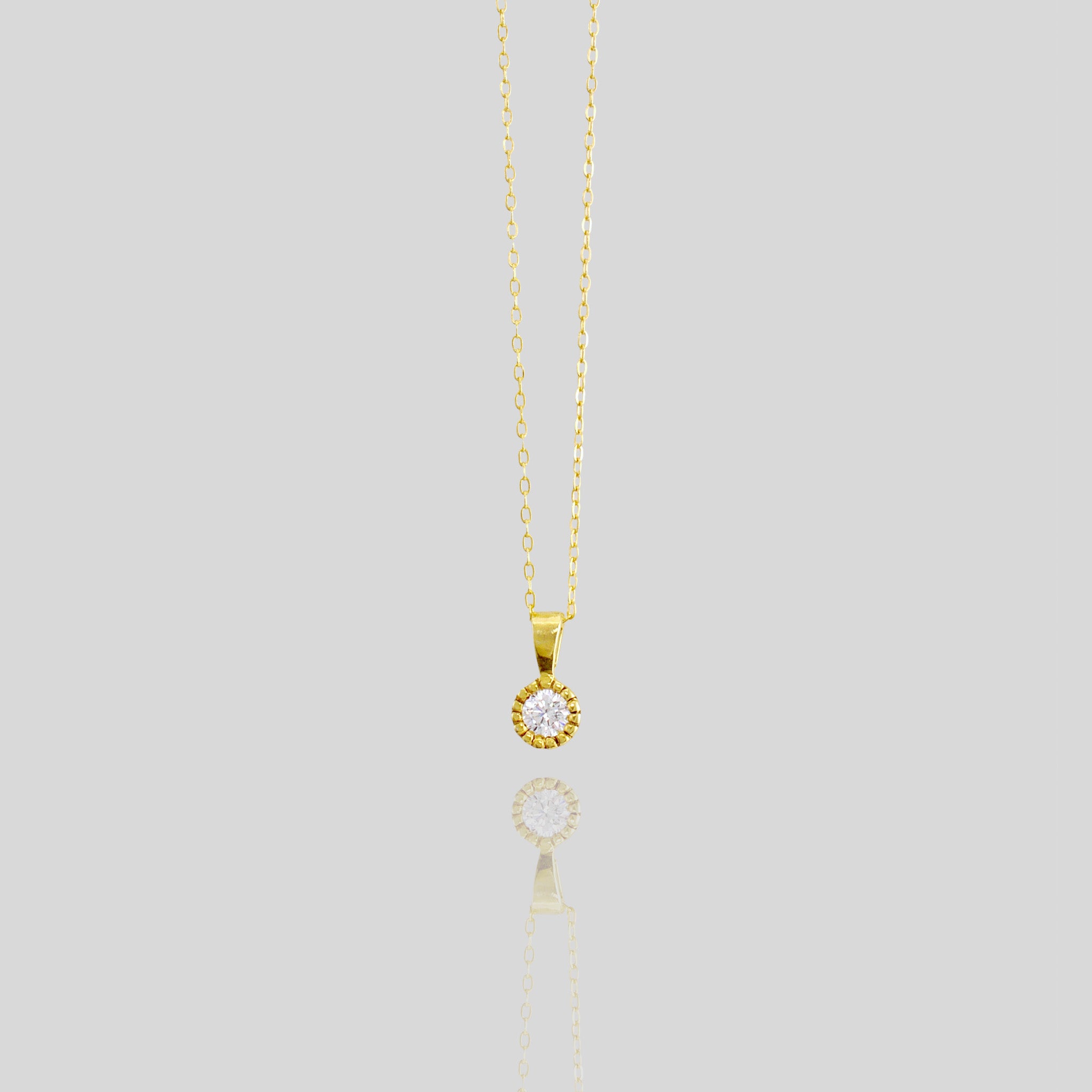 Elegant round gold pendant with embroidered texture and central diamond, exuding classic sophistication.