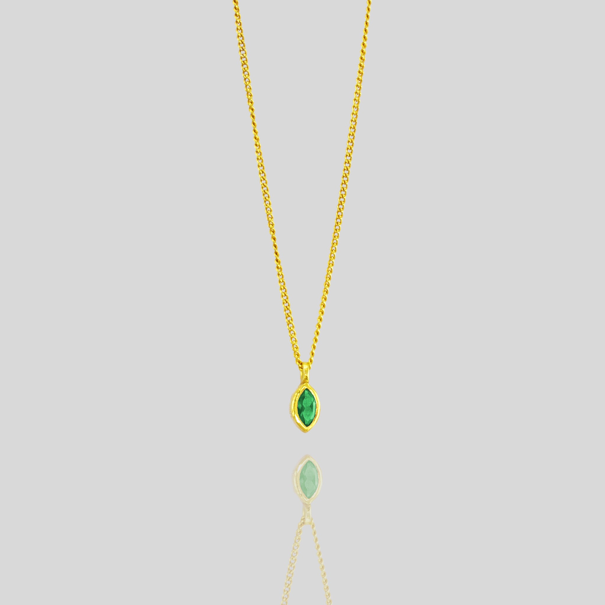 Elegant marquee gold pendant featuring a small, exquisite emerald, adding a delicate touch of vibrant green to enhance any outfit with sophistication.