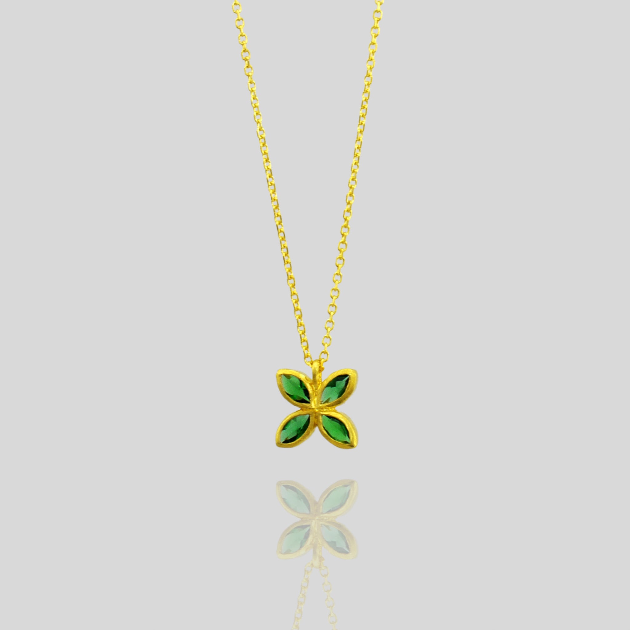 Close up of an Elegant gold pendant with four marquise-cut Emeralds arranged into a delicate flower design, offering luxury and beauty suitable for any gift occasion.