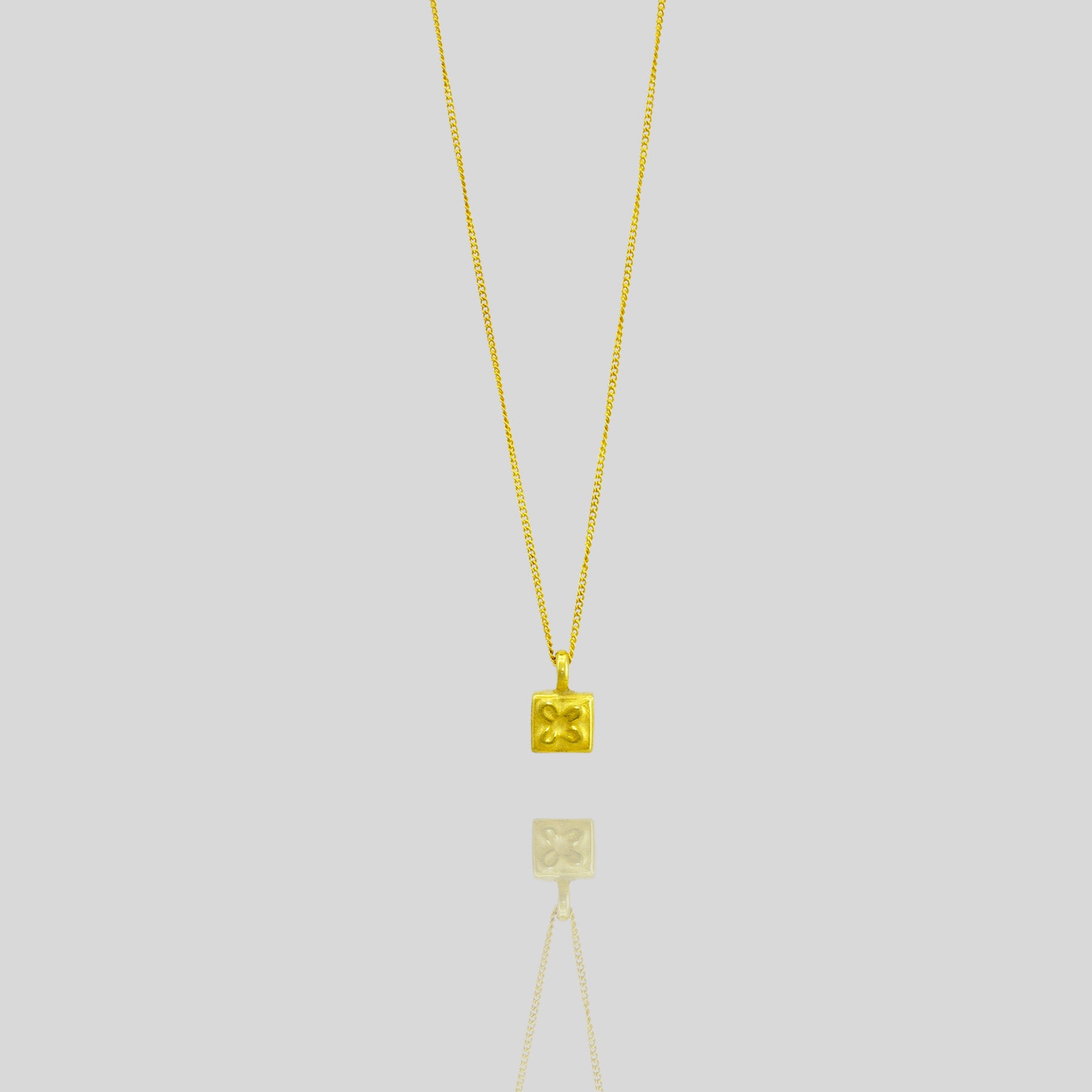 Handcrafted 18k Gold Pendant with a delicate square shape and a small flower at the center, showcasing elegance and careful craftsmanship.
